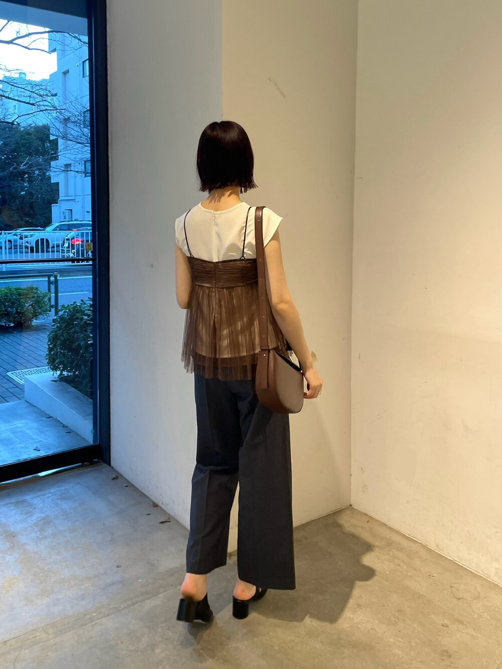 ブラウン系のTシャツ/カットソー、ブルー系のスラックス、ブラック系のサンダルを着用したレディースの春コーディネートの4枚目の写真