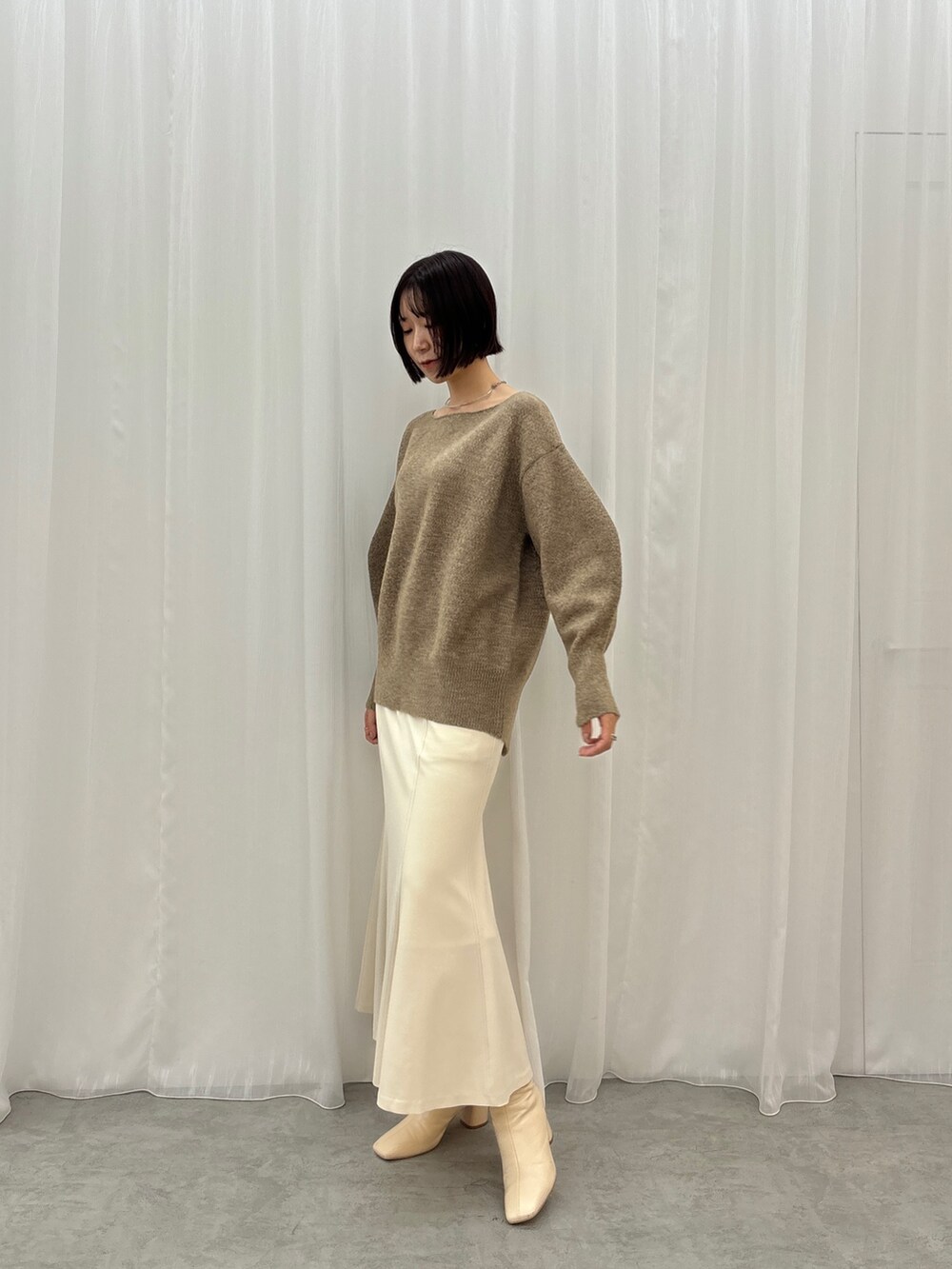ブラウン系のニット/セーター、ホワイト系のスカートを着用したレディースの秋コーディネートの2枚目の写真