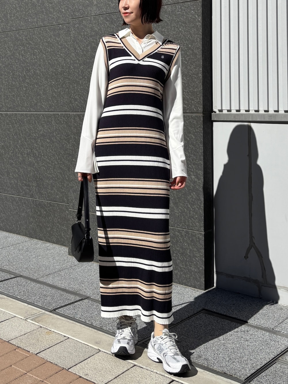 ベージュ系のワンピース、ブラック系のハンドバッグ、ブラウン系のブルゾンを着用したレディースの春コーディネートの7枚目の写真