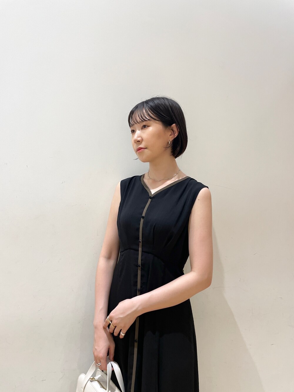 ホワイト系のショルダーバッグ、ベージュ系のサンダル、ブラック系のワンピースを着用したレディースの夏コーディネートの5枚目の写真