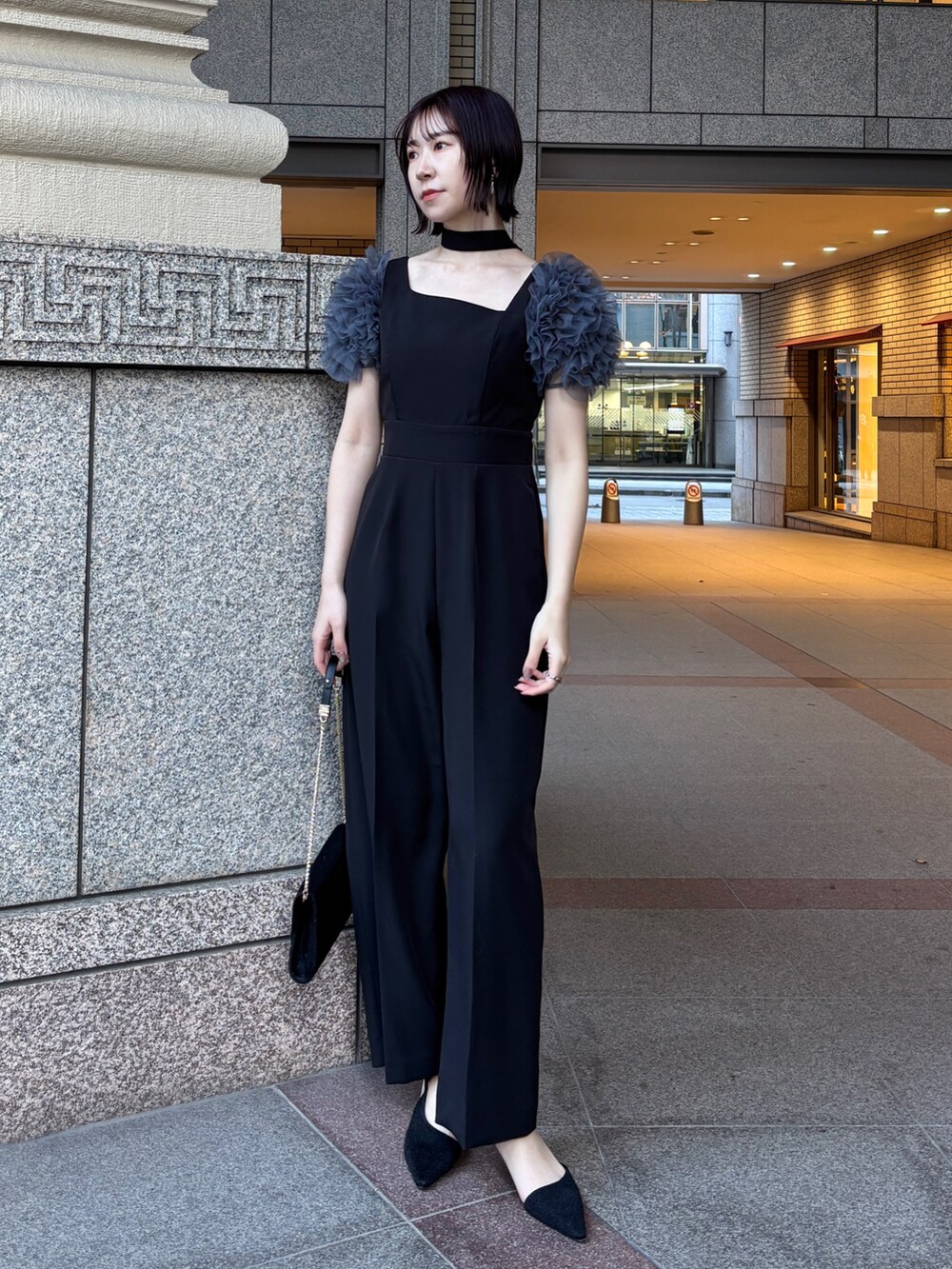 ブラック系のドレス、ブラック系のチェスターコート、ブラック系のハンドバッグを着用したレディースの冬コーディネートの7枚目の写真