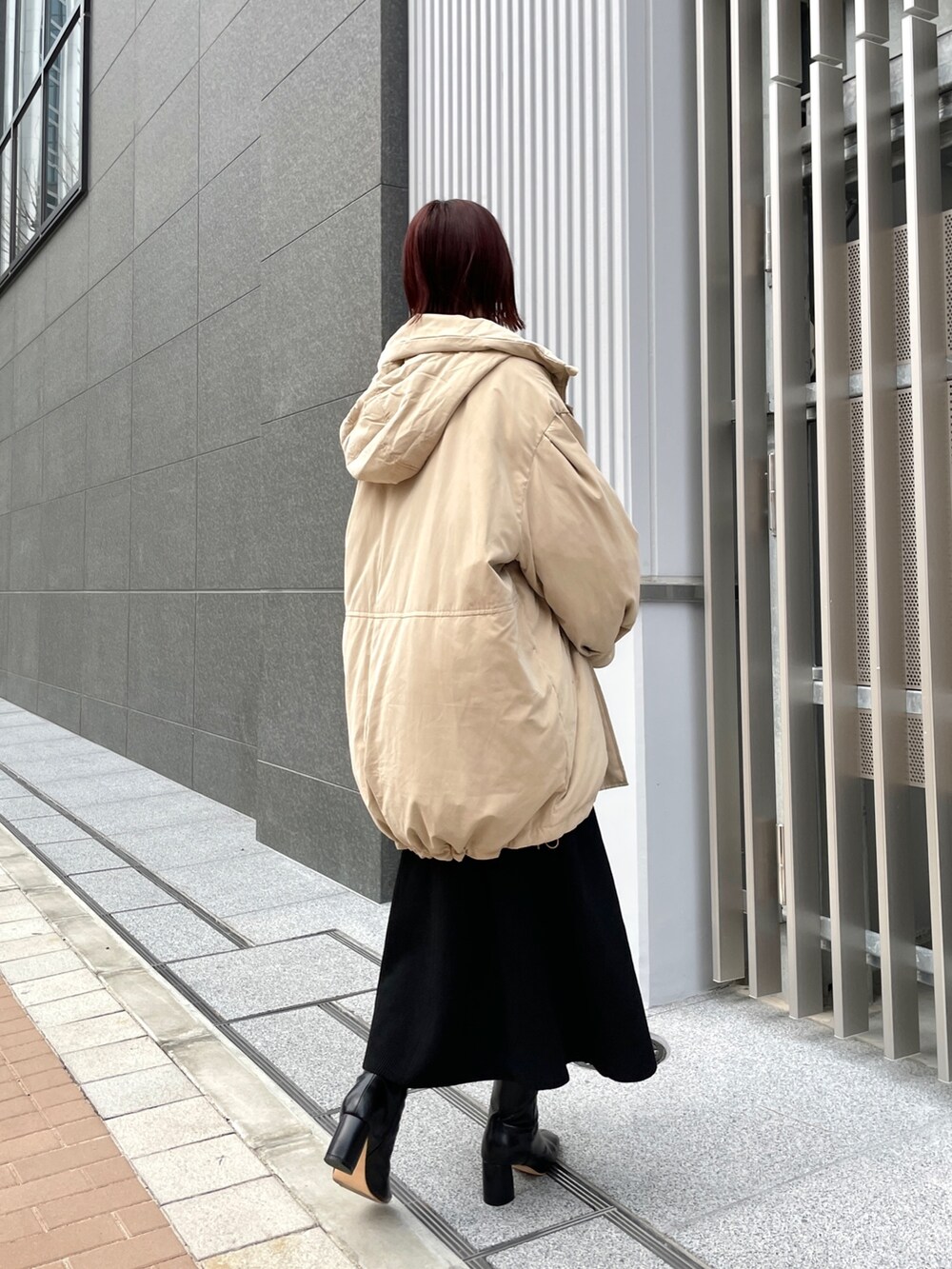 ホワイト系のニット/セーター、ブラック系のジャンパースカート、ブラック系のブーツを着用したレディースの冬コーディネートの8枚目の写真