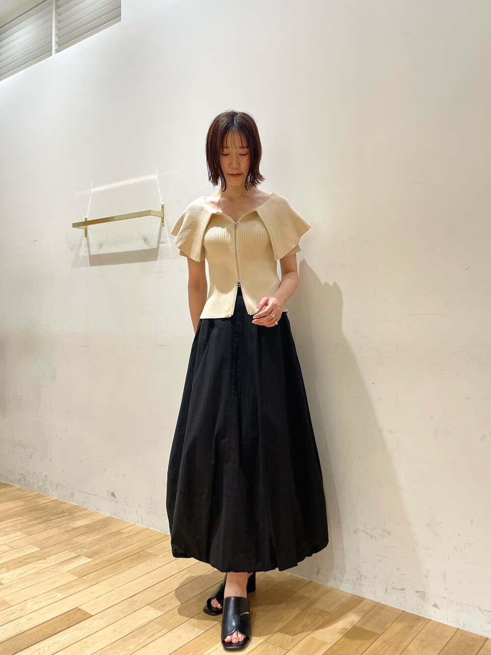 ブラック系のサンダル、ホワイト系のニット/セーター、ブラック系のスカートを着用したレディースの夏コーディネートの5枚目の写真