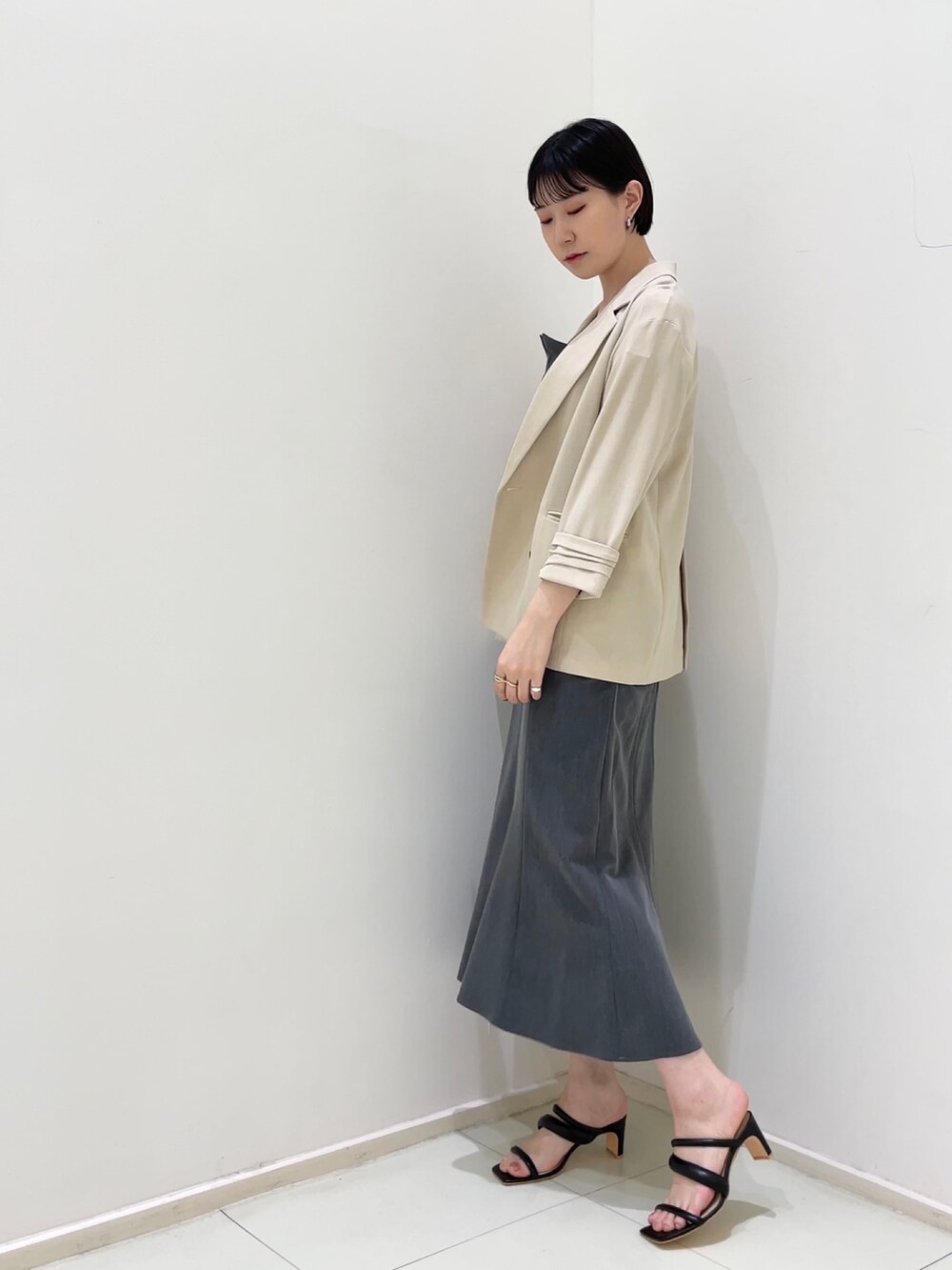 ベージュ系のテーラードジャケット、グレー系のワンピース、ブラック系のサンダルを着用したレディースの春コーディネートの3枚目の写真