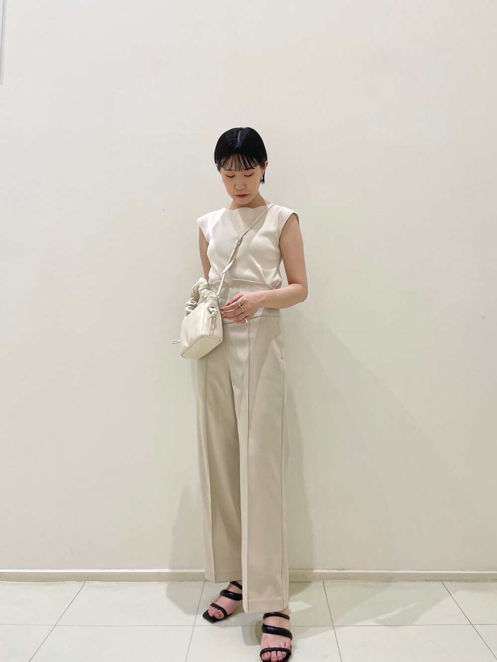 ブラック系のサンダル、ホワイト系のハンドバッグ、ホワイト系のその他パンツを着用したレディースの春コーディネートの2枚目の写真