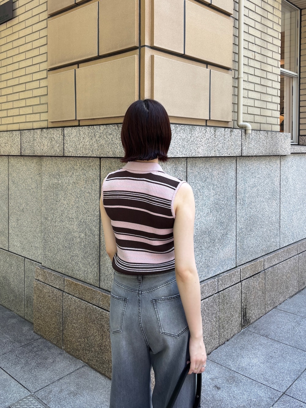 グレー系のデニムパンツ、ピンク系のニット/セーター、ホワイト系のサンダルを着用したレディースの春コーディネートの4枚目の写真