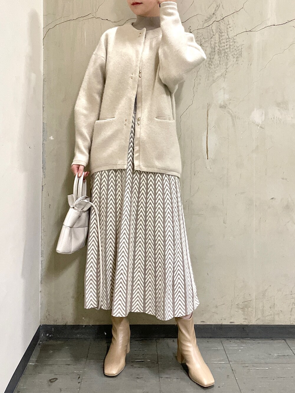 ホワイト系のカーディガン/ボレロ、ベージュ系のブーツ、ホワイト系のハンドバッグを着用したレディースの冬コーディネートの3枚目の写真