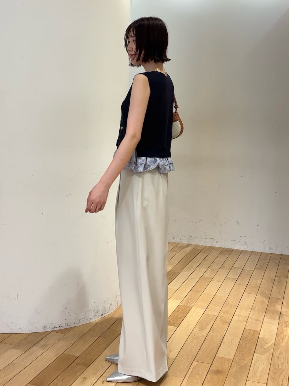 ホワイト系のその他パンツ、ホワイト系のニット/セーター、ブラウン系のハンドバッグを着用したレディースの夏コーディネートの2枚目の写真