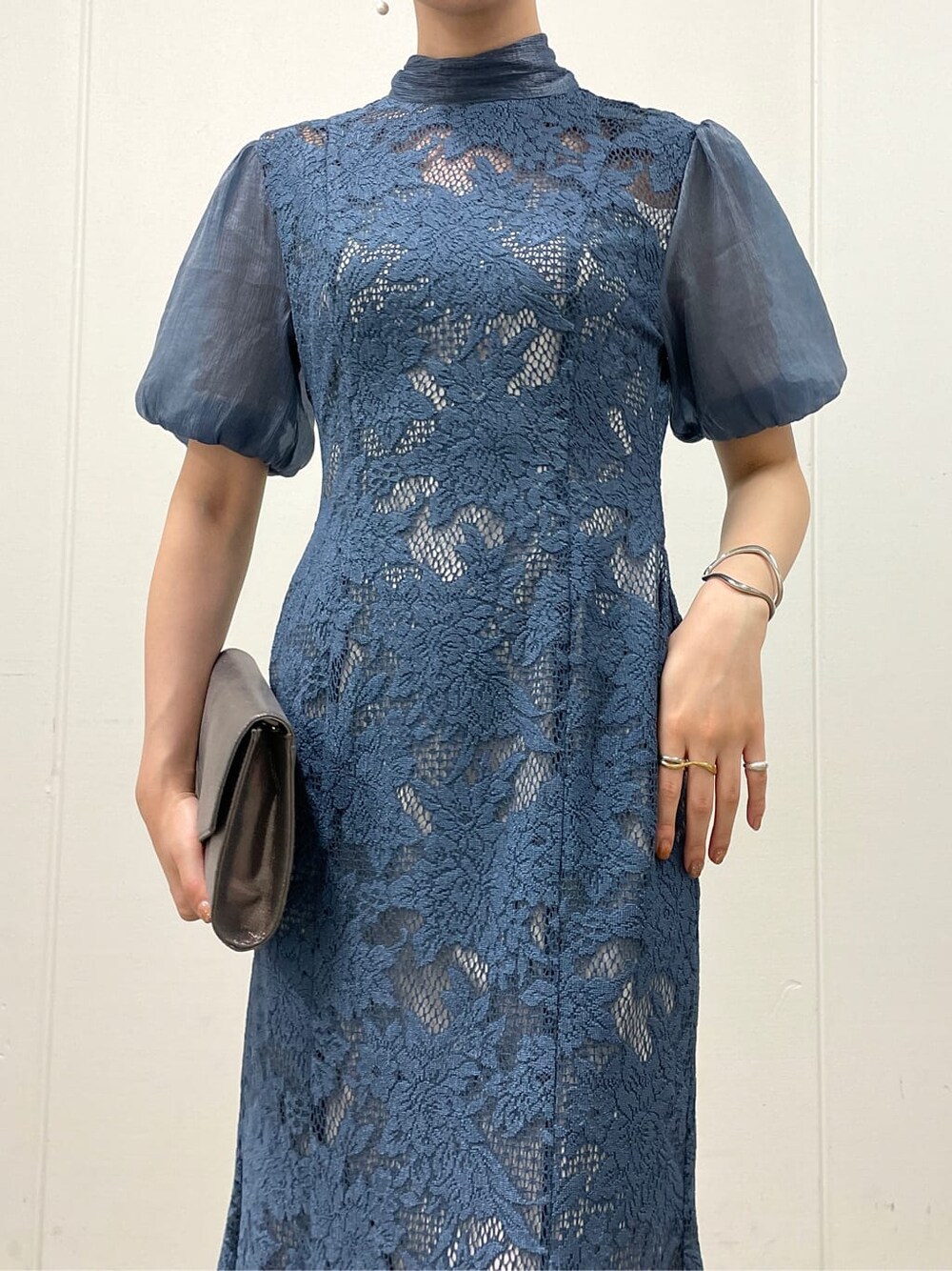 シルバー系のクラッチバッグ、ベージュ系のパンプス、ブルー系のドレスを着用したレディースの夏コーディネートの6枚目の写真