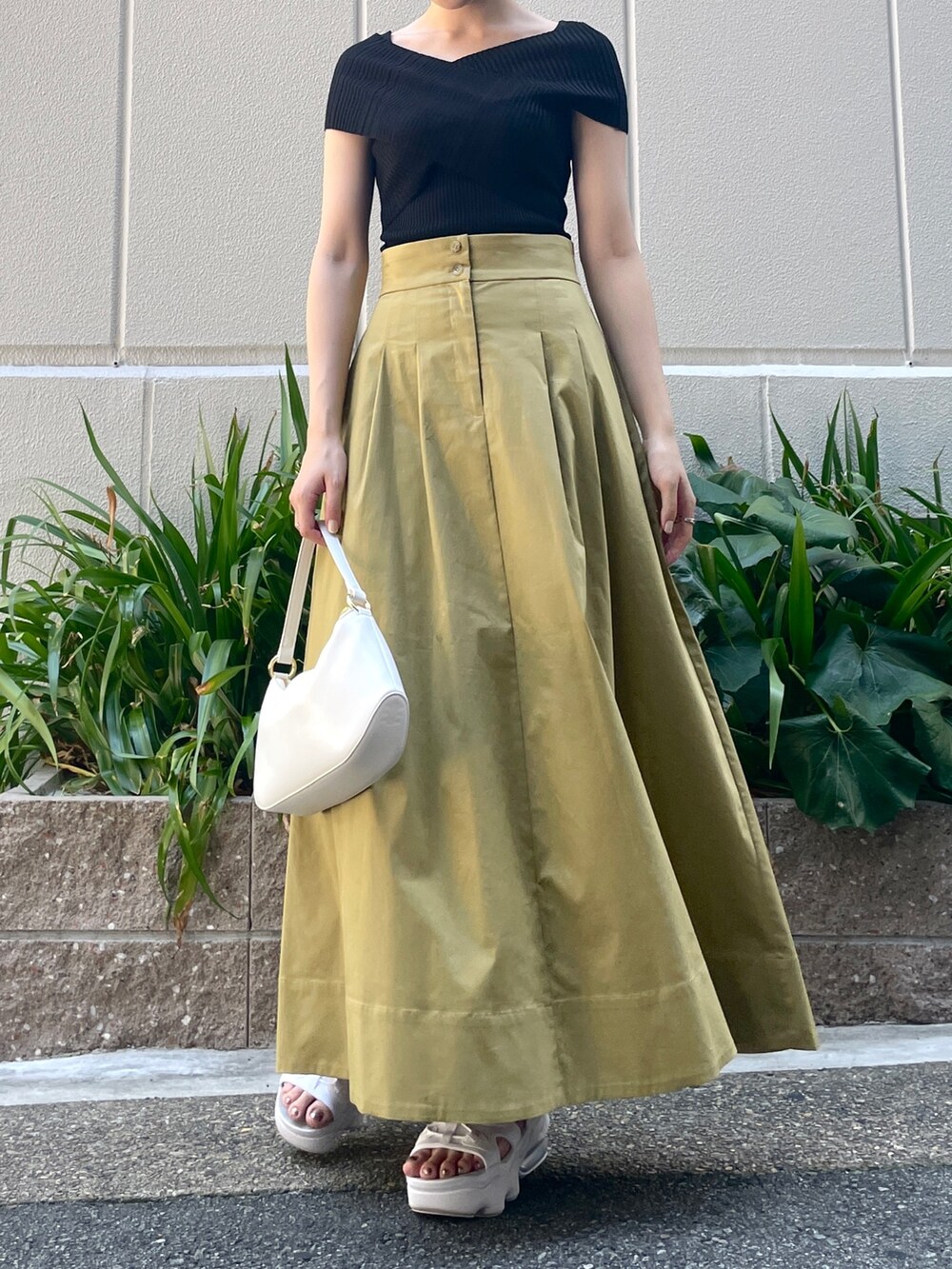 ブラック系のニット/セーター、イエロー系のスカート、ホワイト系のハンドバッグを着用したレディースの夏コーディネートの4枚目の写真