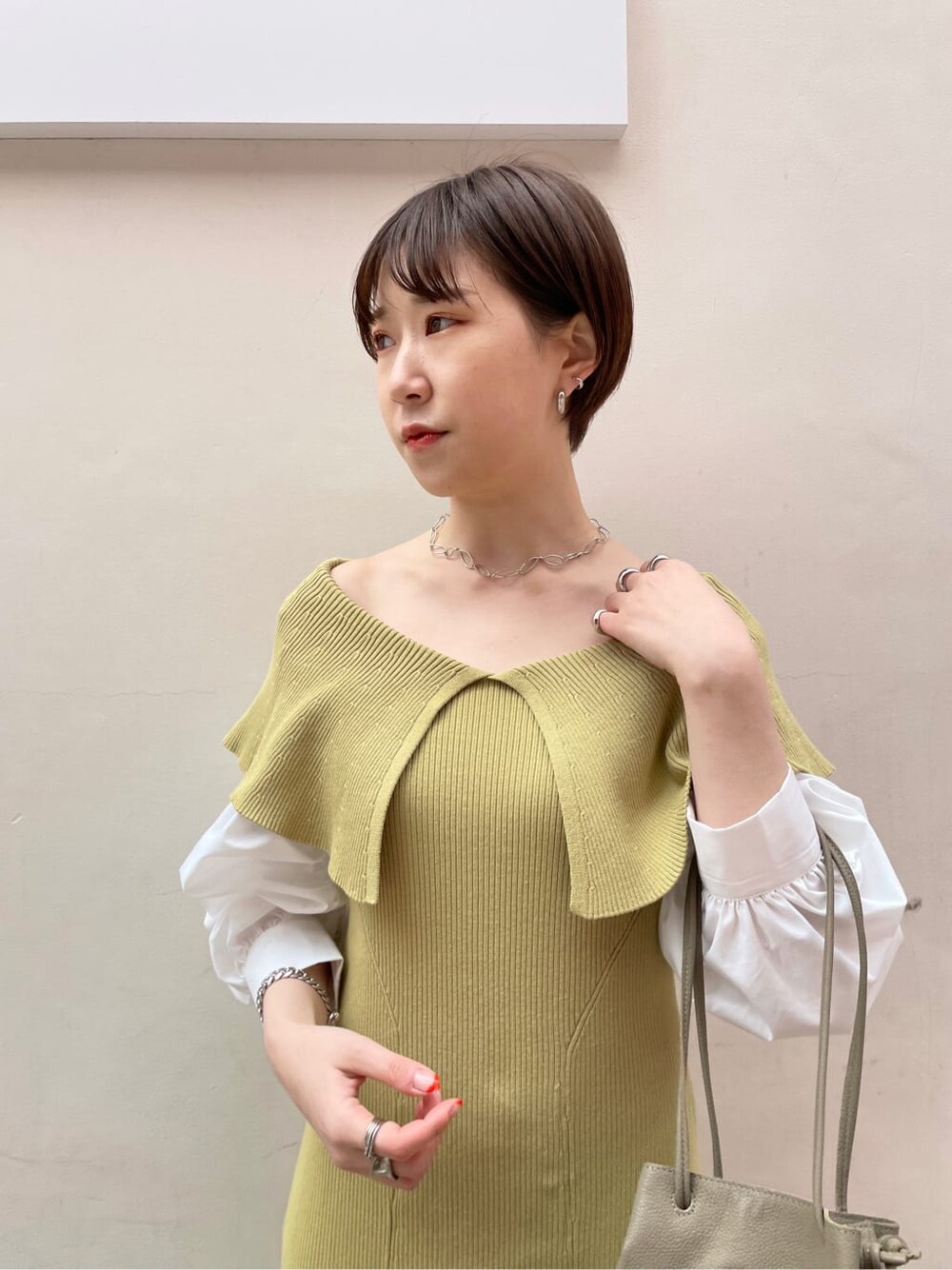 ベージュ系のハンドバッグ、ベージュ系のトレンチコート、イエロー系のワンピースを着用したレディースの冬コーディネートの6枚目の写真