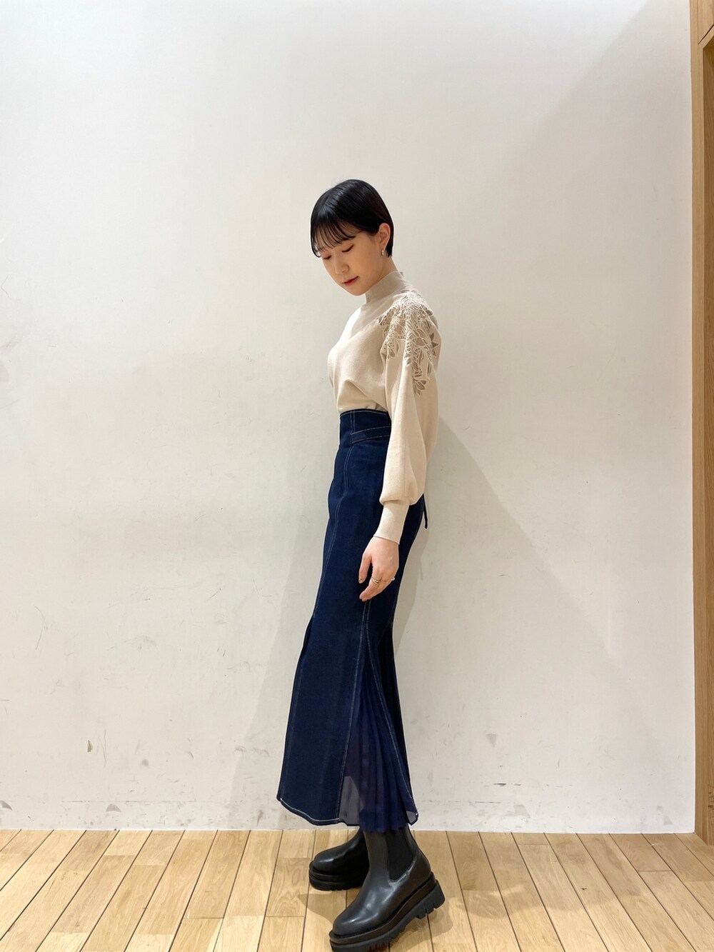 ホワイト系のニット/セーター、ブルー系のスカート、ブラック系のブーツを着用したレディースの冬コーディネートの3枚目の写真