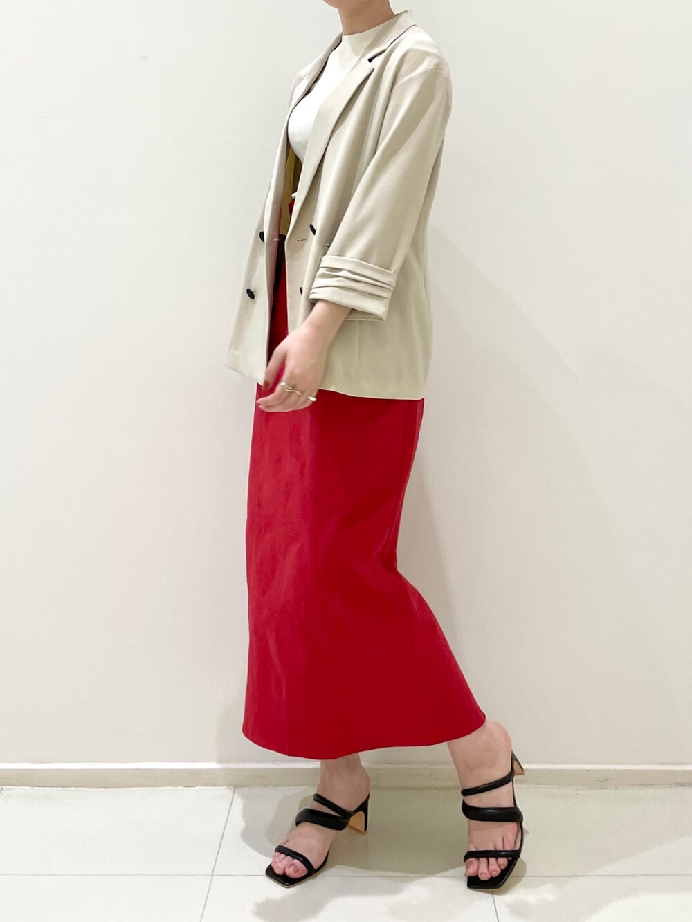レッド系のスカート、ブラック系のサンダル、ベージュ系のテーラードジャケットを着用したレディースの春コーディネートの5枚目の写真