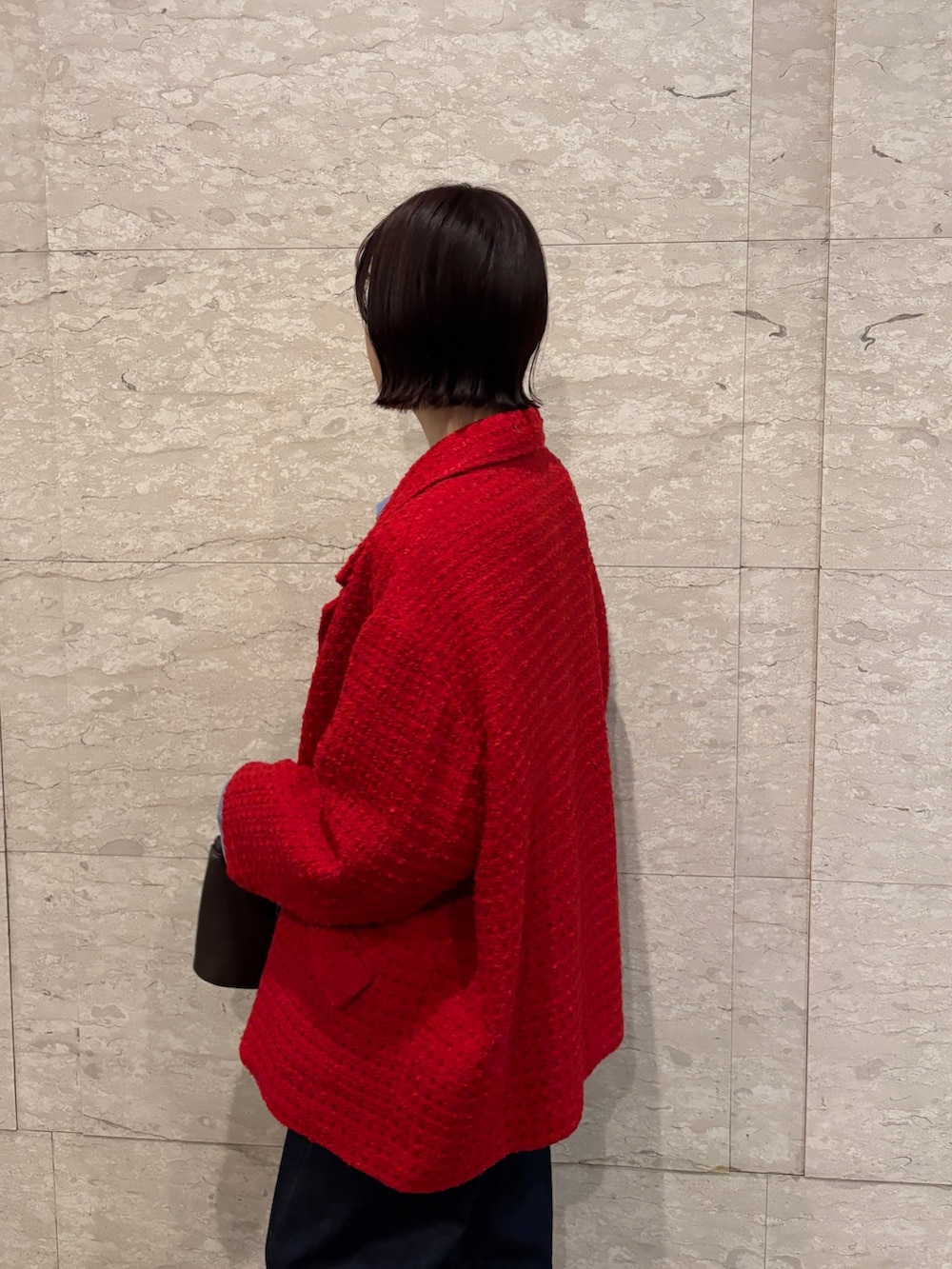 ブルー系のデニムパンツ、ブラウン系のニット/セーター、ブラウン系のハンドバッグを着用したレディースの冬コーディネートの4枚目の写真