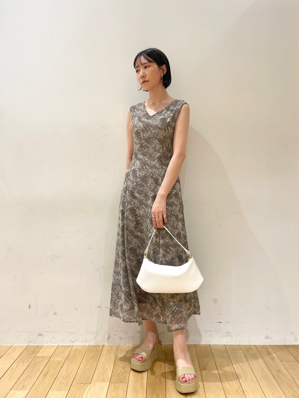 グレー系のワンピース、ホワイト系のハンドバッグ、ベージュ系のサンダルを着用したレディースの夏コーディネートの6枚目の写真