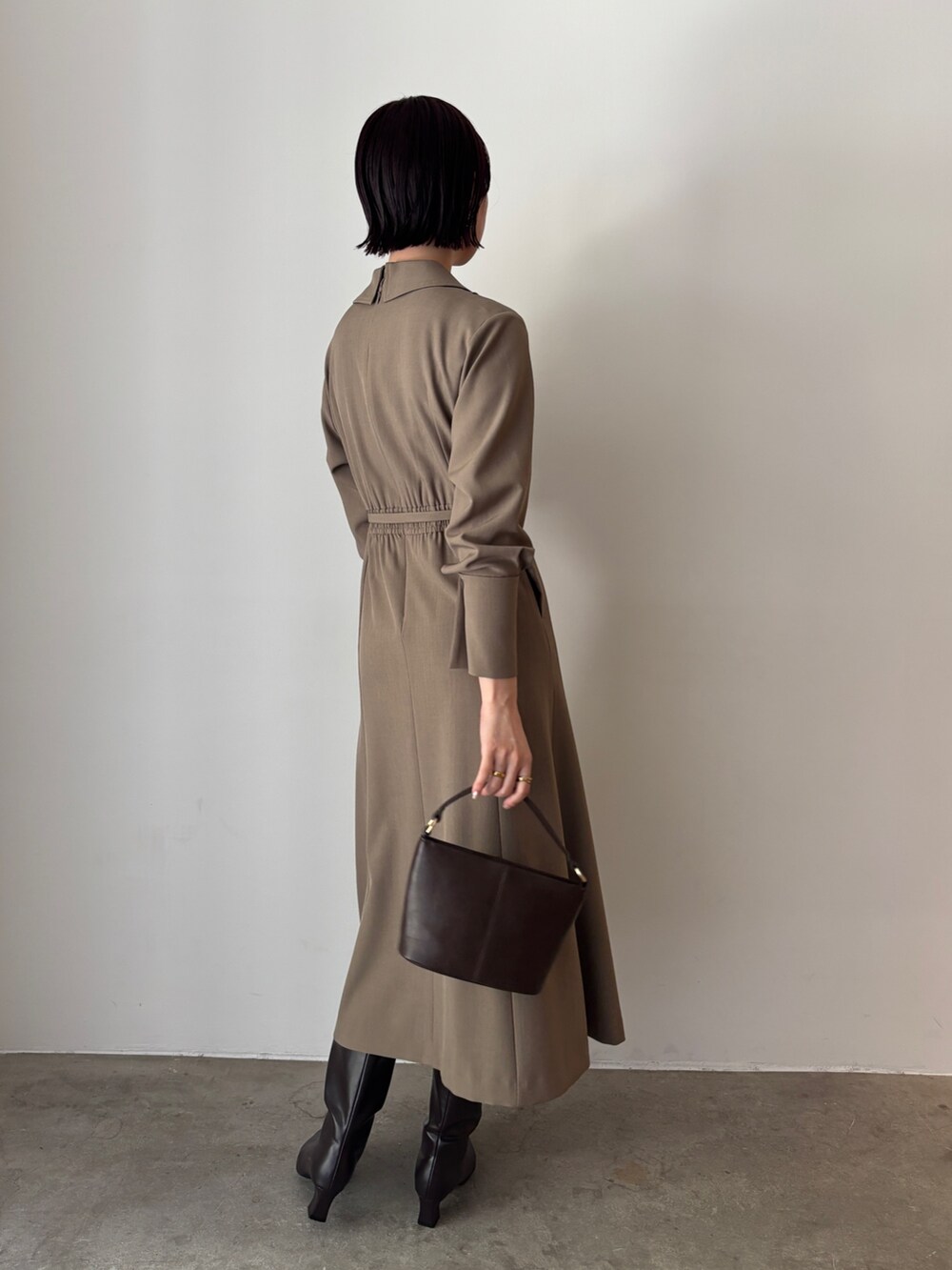 ホワイト系のワンピース、ブラウン系のハンドバッグ、ブラウン系のブーツを着用したレディースの秋コーディネートの3枚目の写真