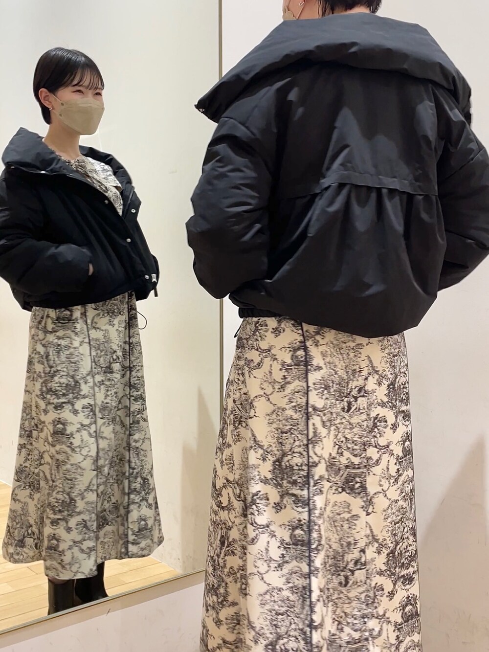 ブラック系のダウンジャケット/コート、ホワイト系のワンピース、ブラック系のブーツを着用したレディースの冬コーディネートの2枚目の写真