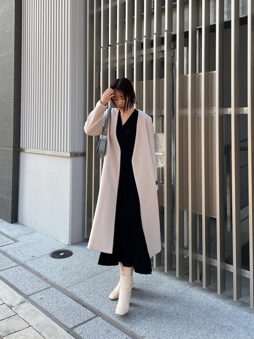 ブラック系のワンピース、ブルー系のショルダーバッグ、ホワイト系のブーツを着用したレディースの冬コーディネートの7枚目の写真