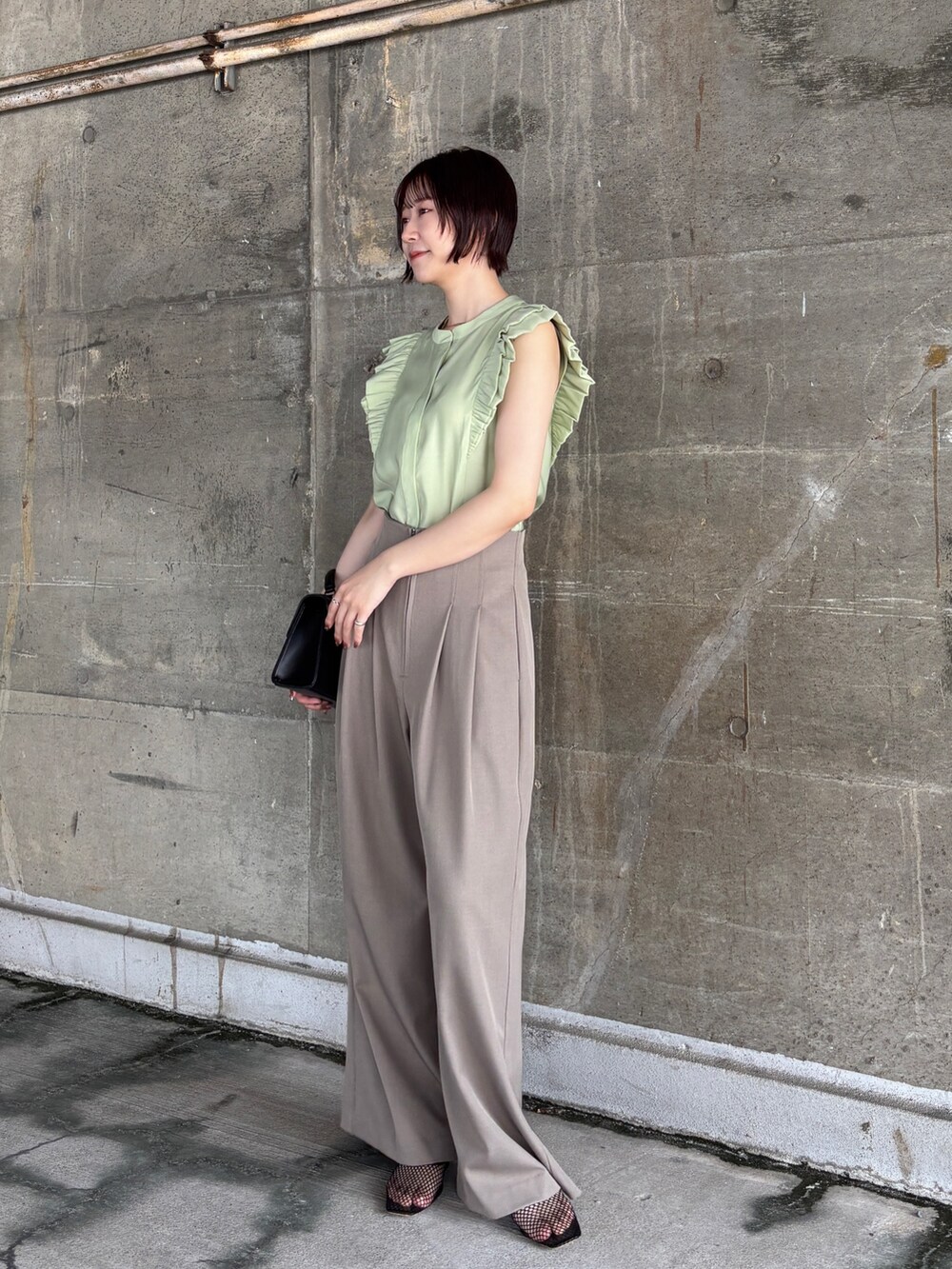 ブラウン系のその他パンツ、グリーン系のシャツ/ブラウス、ブラック系のハンドバッグを着用したレディースの夏コーディネートの3枚目の写真