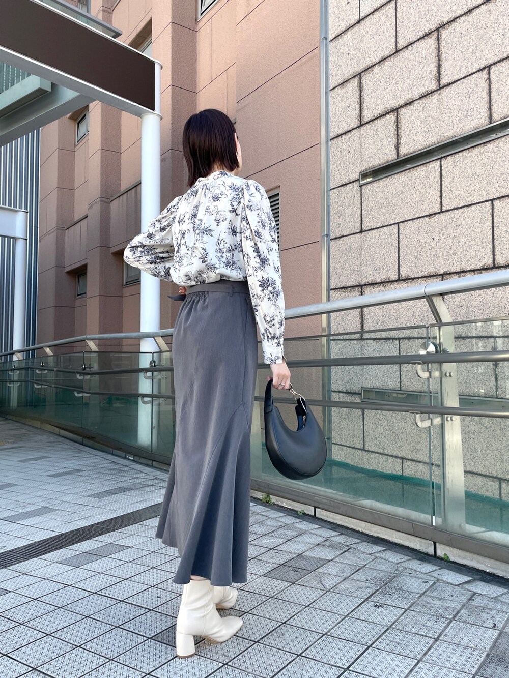 グレー系のスカート、ホワイト系のシャツ/ブラウス、ホワイト系のブーツを着用したレディースの秋コーディネートの3枚目の写真