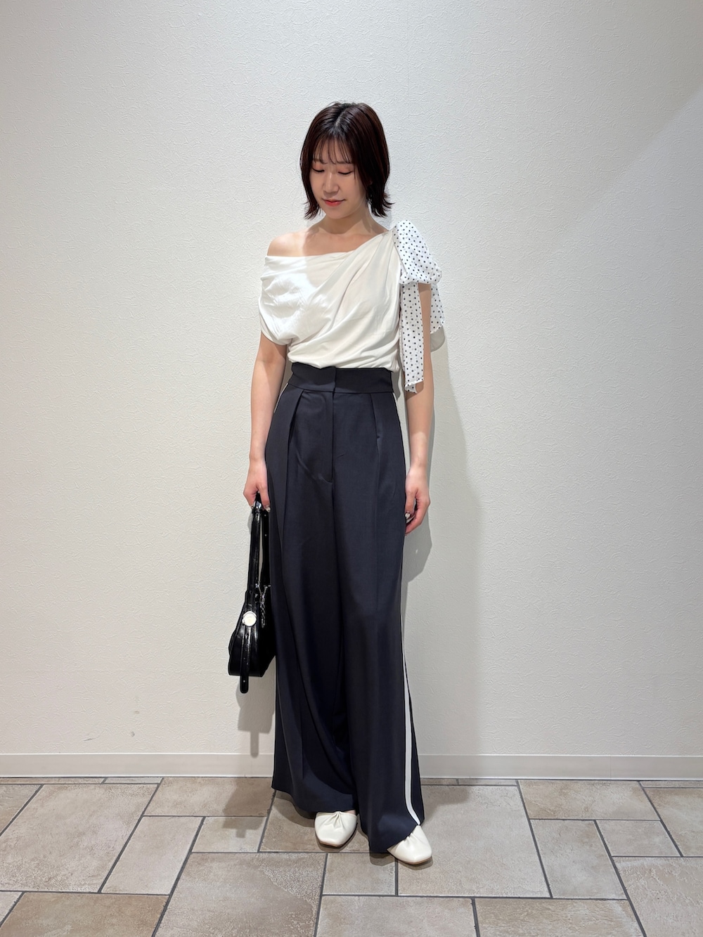 グレー系のその他パンツ、ホワイト系のサンダル、ブラック系のハンドバッグを着用したレディースの夏コーディネートの2枚目の写真
