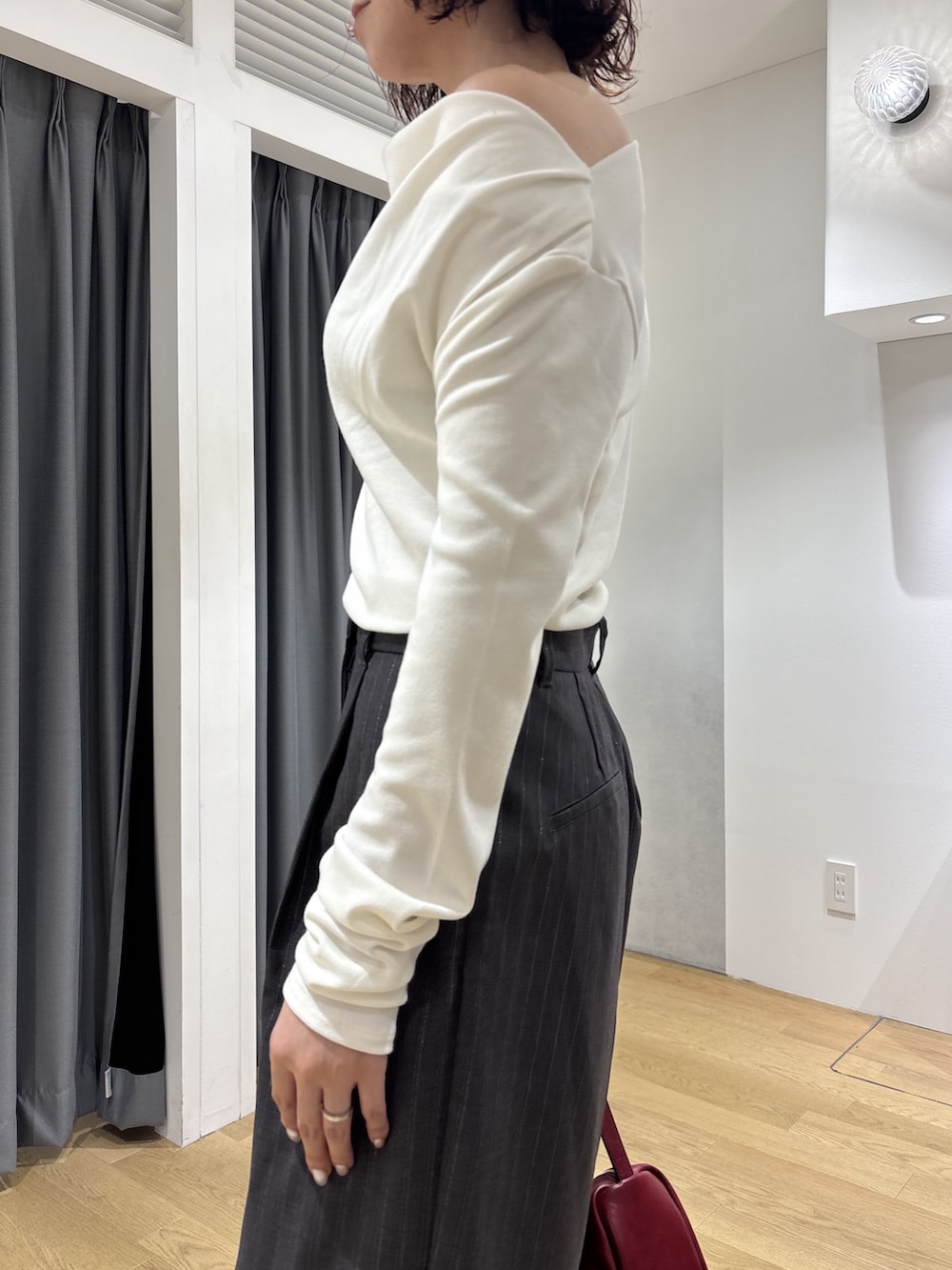 グレー系のその他パンツ、ホワイト系のニット/セーター、レッド系のハンドバッグを着用したレディースの秋コーディネートの5枚目の写真