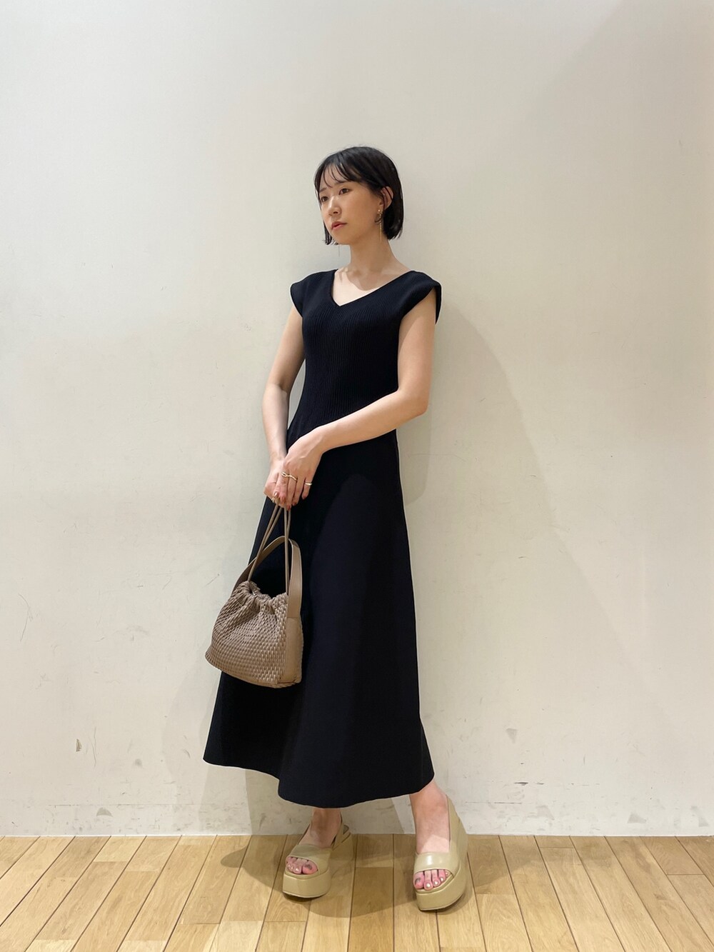 ブラック系のワンピース、ブラウン系のハンドバッグ、ベージュ系のサンダルを着用したレディースの夏コーディネートの2枚目の写真