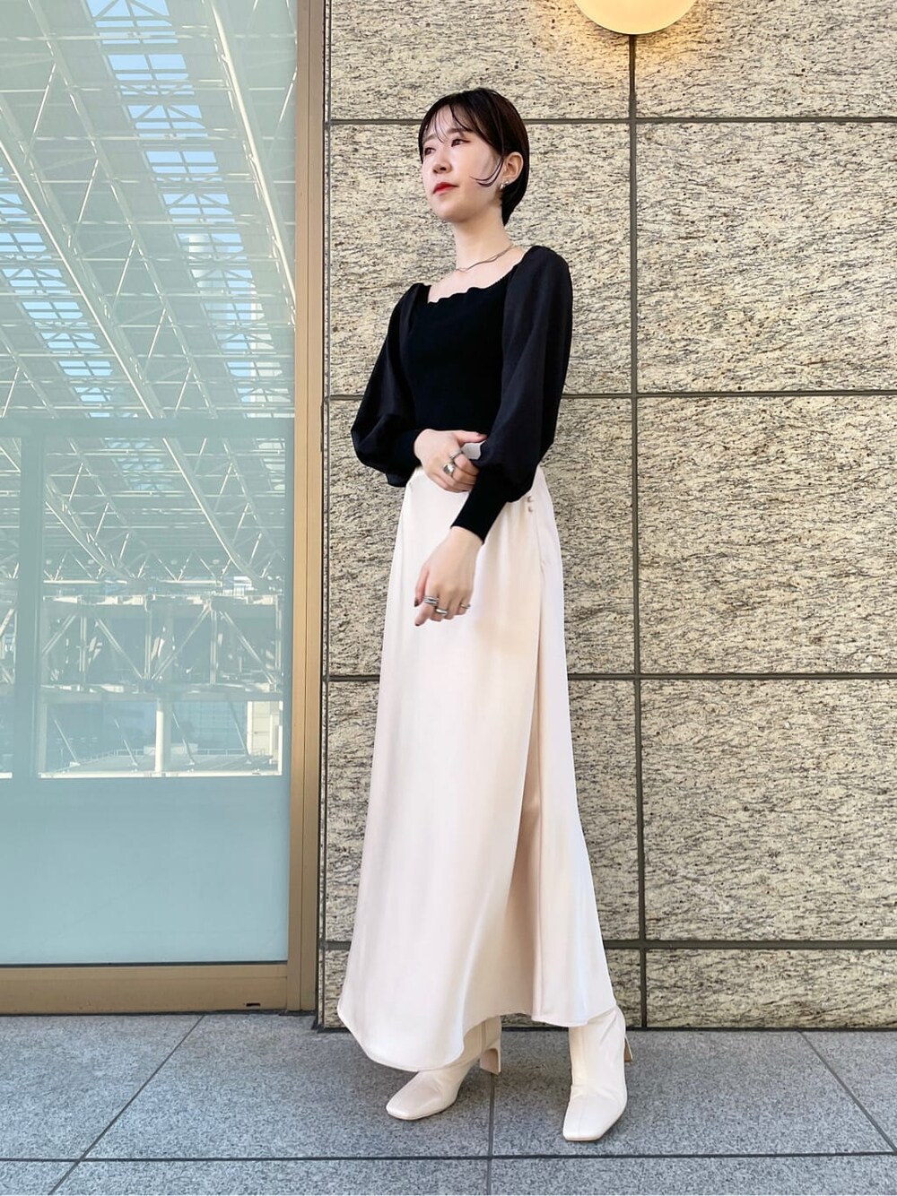 ホワイト系のスカート、ホワイト系のノーカラーコート、ブラック系のニット/セーターを着用したレディースの冬コーディネートの5枚目の写真