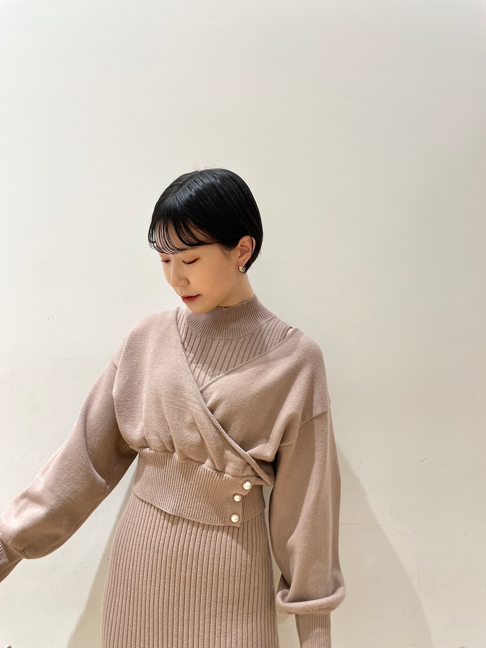 ベージュ系のワンピース、ホワイト系のハンドバッグ、ブラック系のブーツを着用したレディースの冬コーディネートの6枚目の写真