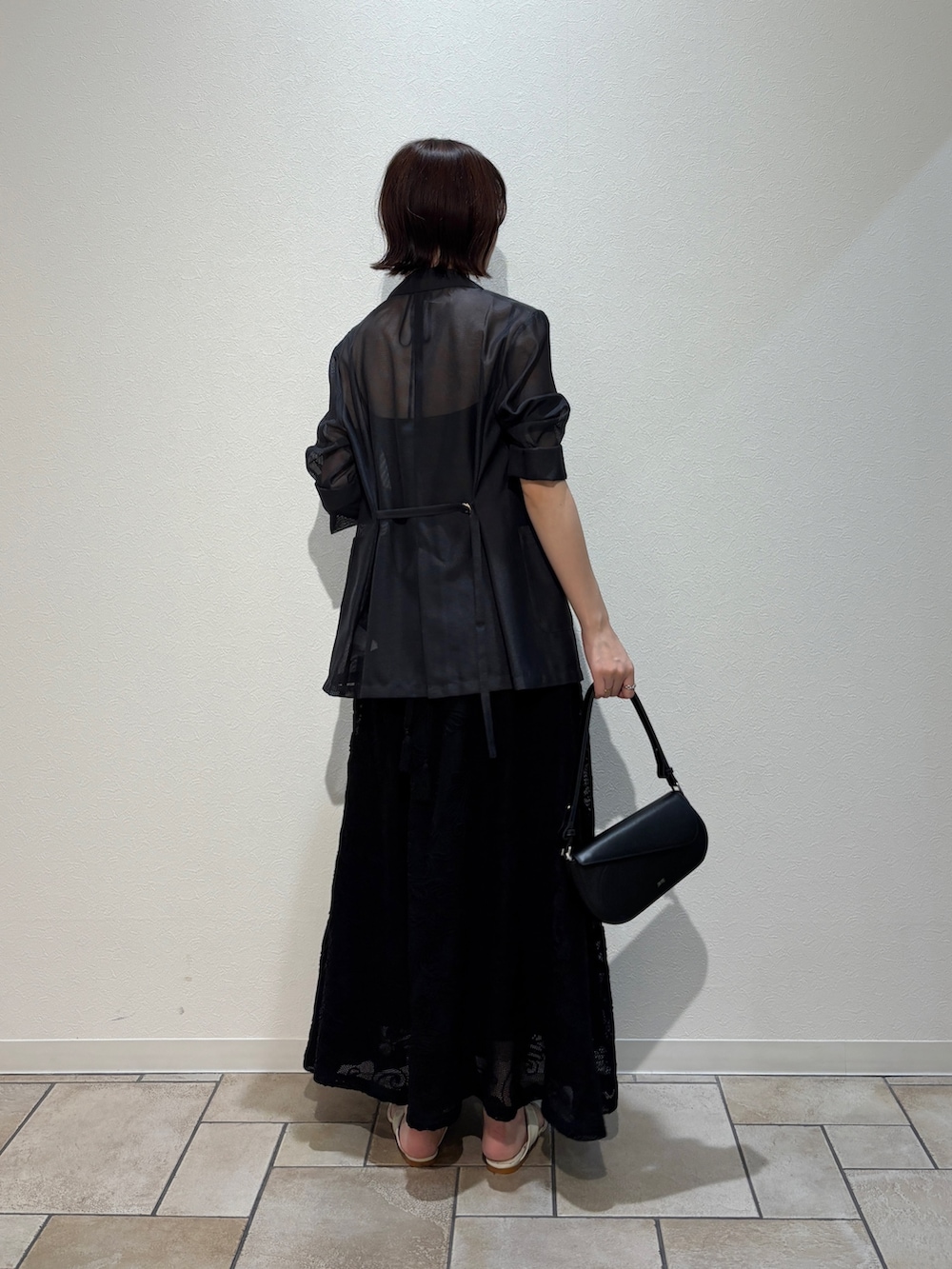 ブラック系のワンピース、ブラック系のハンドバッグ、ホワイト系のサンダルを着用したレディースの夏コーディネートの7枚目の写真