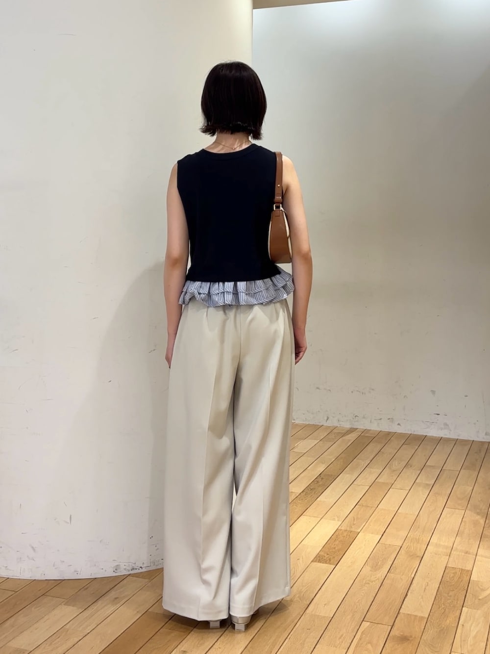 ホワイト系のその他パンツ、ホワイト系のニット/セーター、ブラウン系のハンドバッグを着用したレディースの夏コーディネートの3枚目の写真