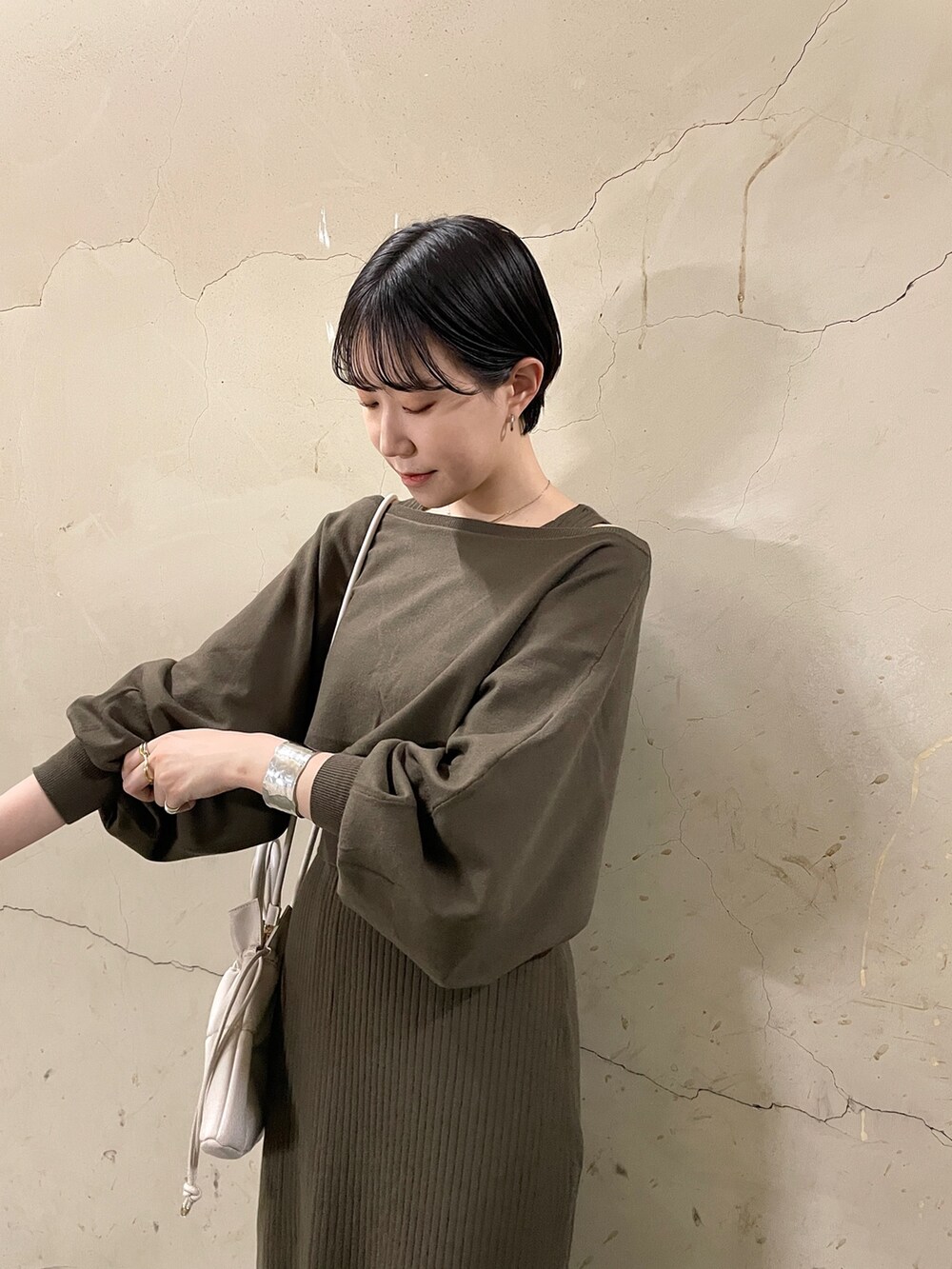 ブラウン系のワンピース、ブラック系のブーツ、ホワイト系のハンドバッグを着用したレディースの秋コーディネートの5枚目の写真