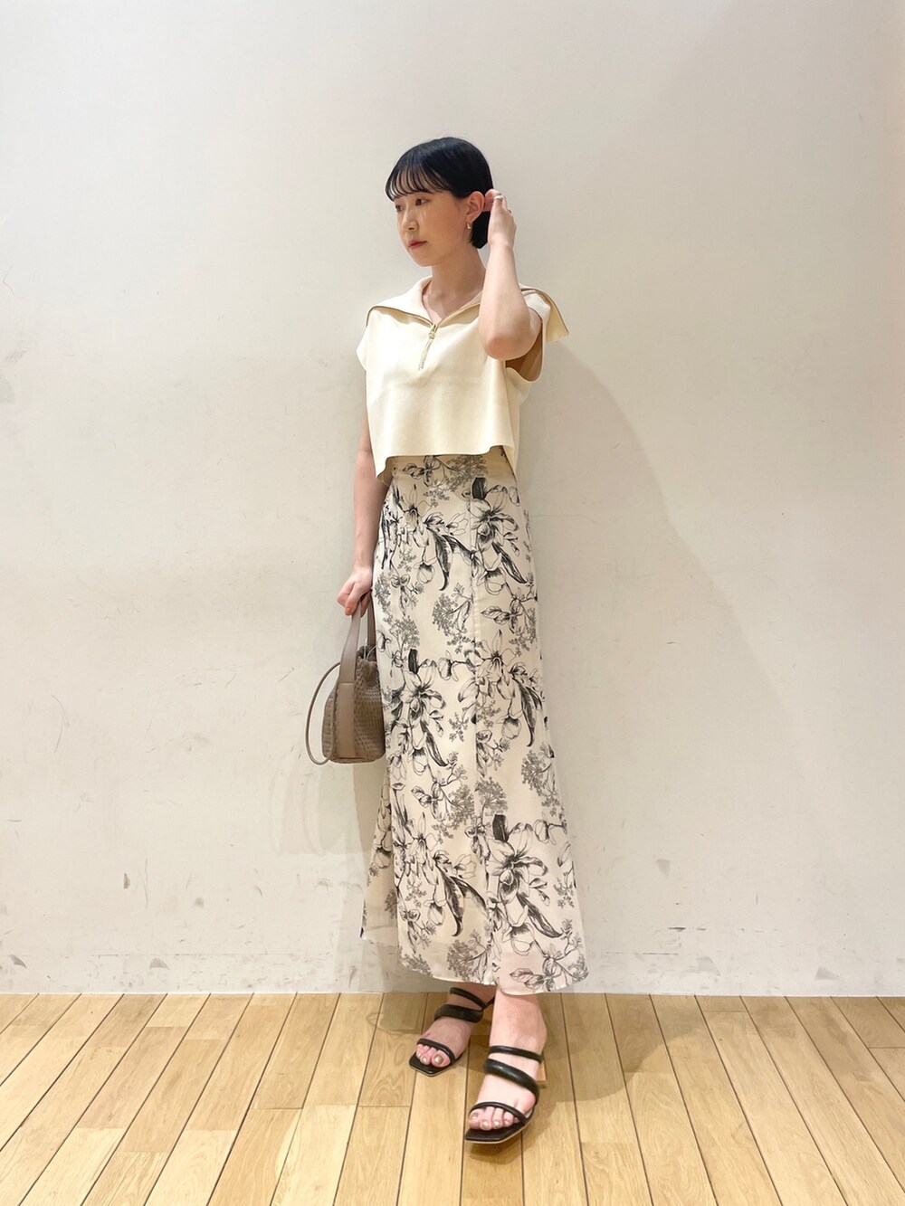 ホワイト系のニット/セーター、ホワイト系のスカート、ブラウン系のハンドバッグを着用したレディースの春コーディネートの2枚目の写真