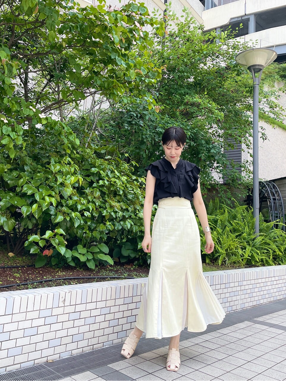 ホワイト系のスカート、ホワイト系のサンダル、ブラック系のシャツ/ブラウスを着用したレディースの夏コーディネートの3枚目の写真