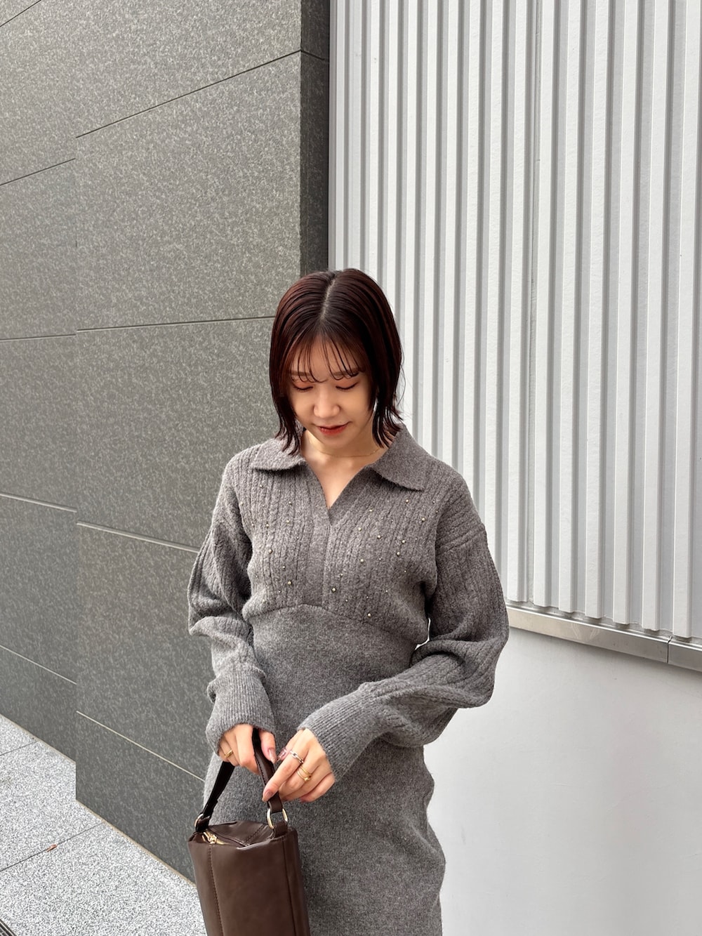 グレー系のワンピース、ブラウン系のハンドバッグ、ブラック系のブーツを着用したレディースの冬コーディネートの4枚目の写真