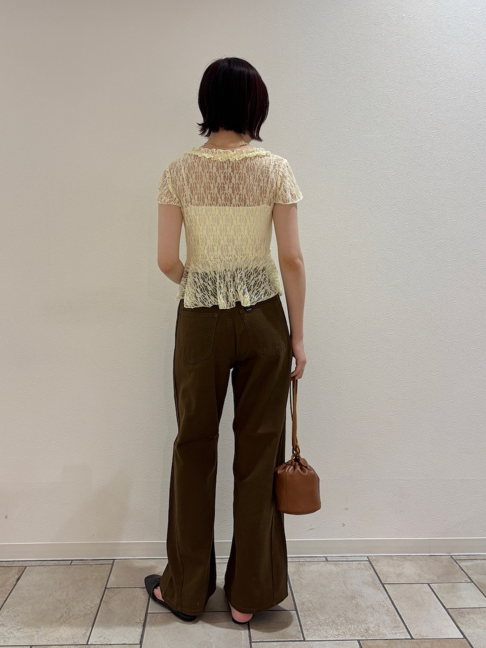 イエロー系のシャツ/ブラウス、ブラウン系のデニムパンツ、イエロー系のハンドバッグを着用したレディースの夏コーディネートの3枚目の写真