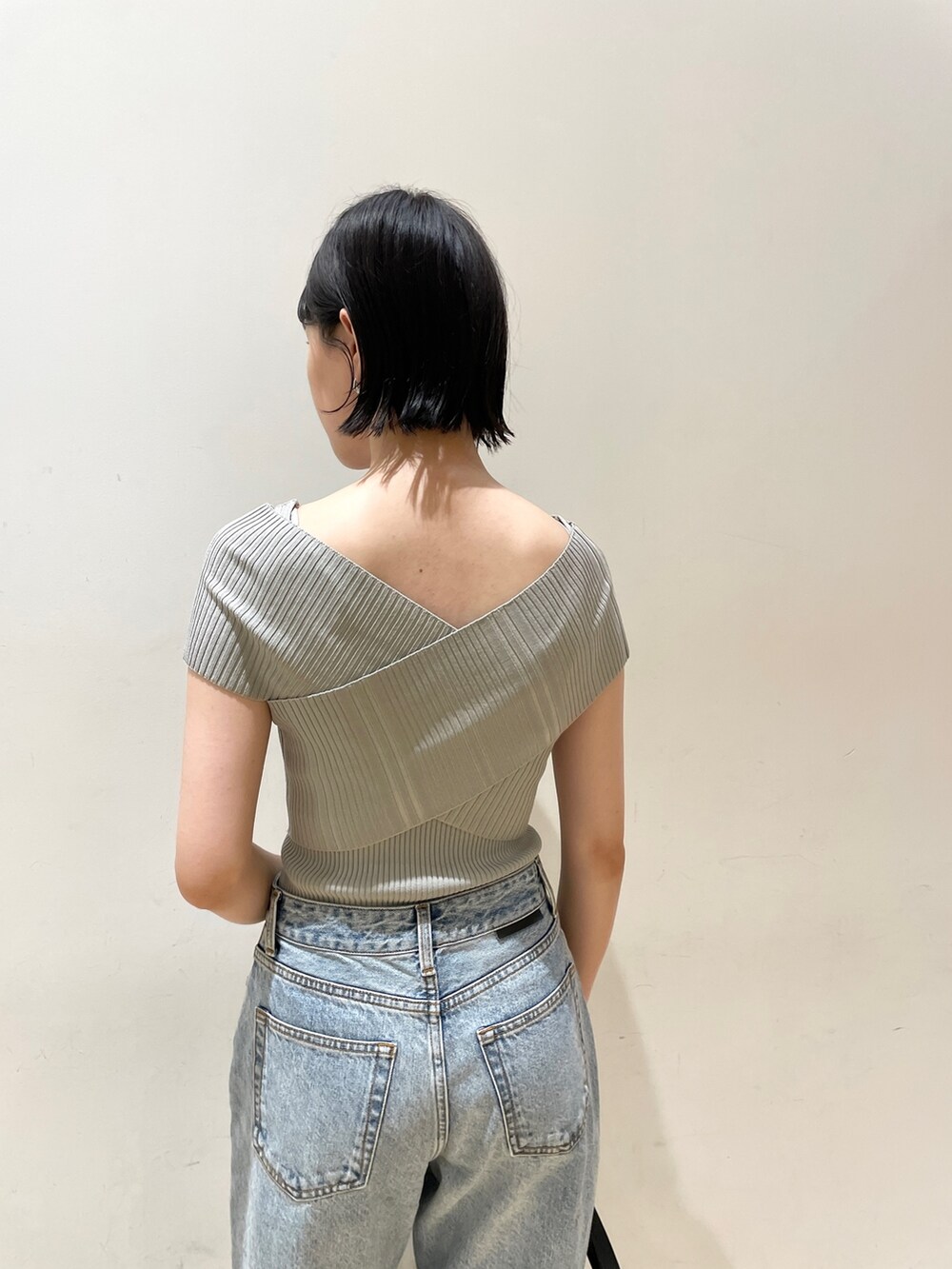 グリーン系のニット/セーター、ブルー系のデニムパンツ、ブラック系のハンドバッグを着用したレディースの夏コーディネートの6枚目の写真