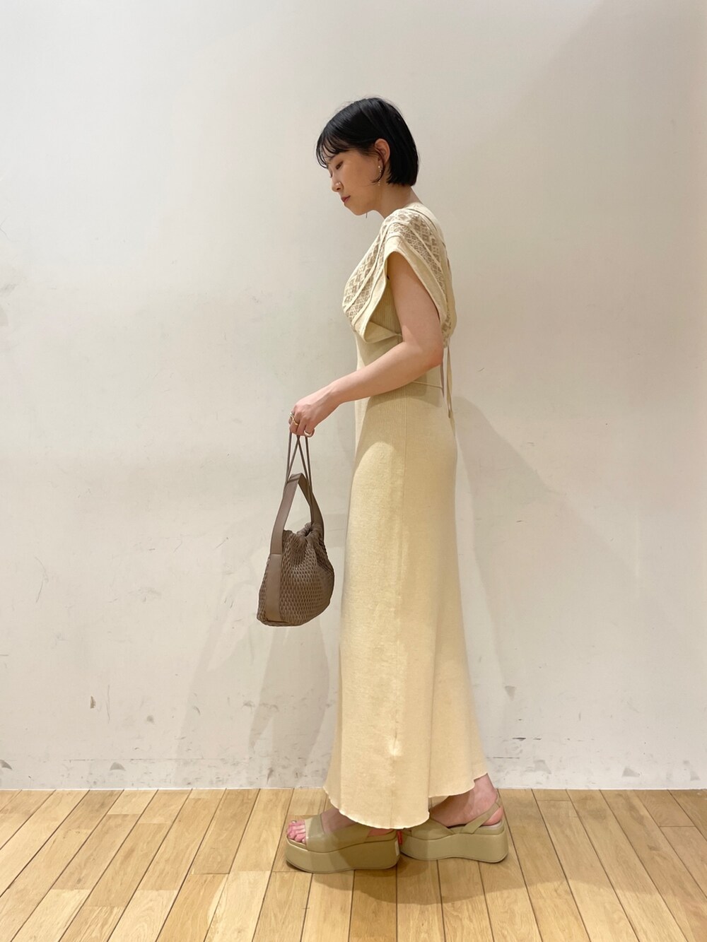 ベージュ系のワンピース、ブラウン系のハンドバッグ、ベージュ系のサンダルを着用したレディースの夏コーディネートの4枚目の写真