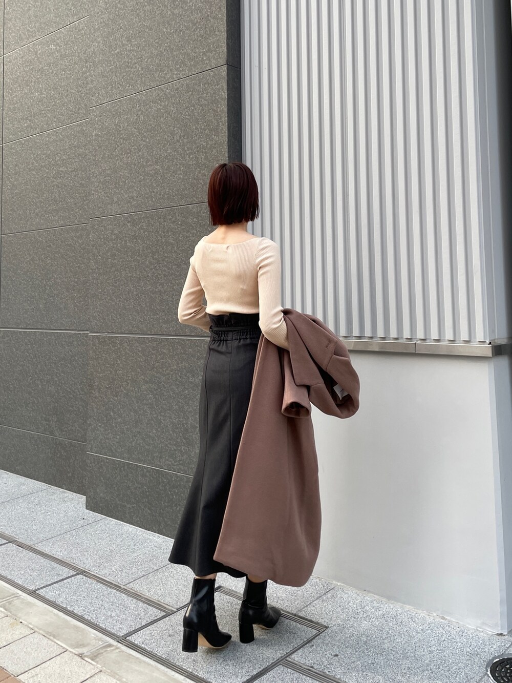 ホワイト系のニット/セーター、ブラウン系のチェスターコート、グレー系のスカートを着用したレディースの冬コーディネートの4枚目の写真