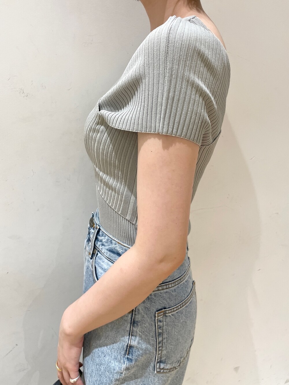 グリーン系のニット/セーター、ブルー系のデニムパンツ、ブラック系のハンドバッグを着用したレディースの夏コーディネートの8枚目の写真