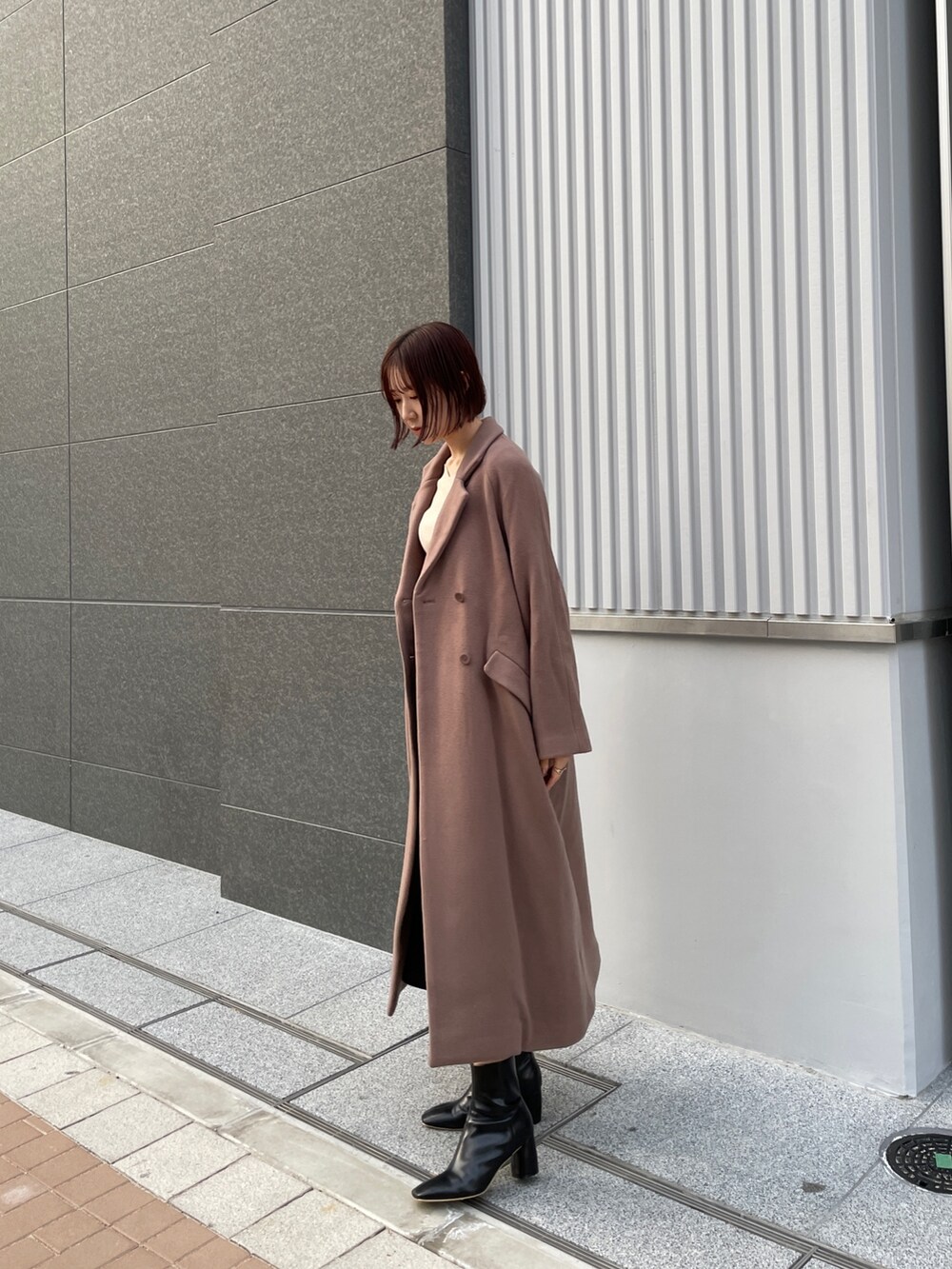 ブラウン系のチェスターコート、ホワイト系のニット/セーター、グレー系のスカートを着用したレディースの冬コーディネートの3枚目の写真