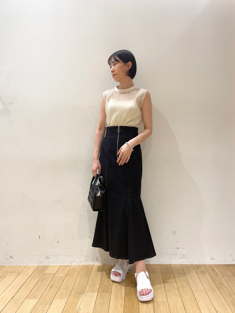 ホワイト系のシャツ/ブラウス、ブラック系のスカート、ブラック系のショルダーバッグを着用したレディースの夏コーディネートの2枚目の写真