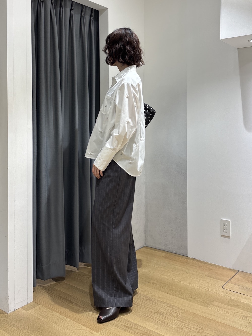 グレー系のその他パンツ、ホワイト系のシャツ/ブラウス、ブラック系のハンドバッグを着用したレディースの秋コーディネートの3枚目の写真
