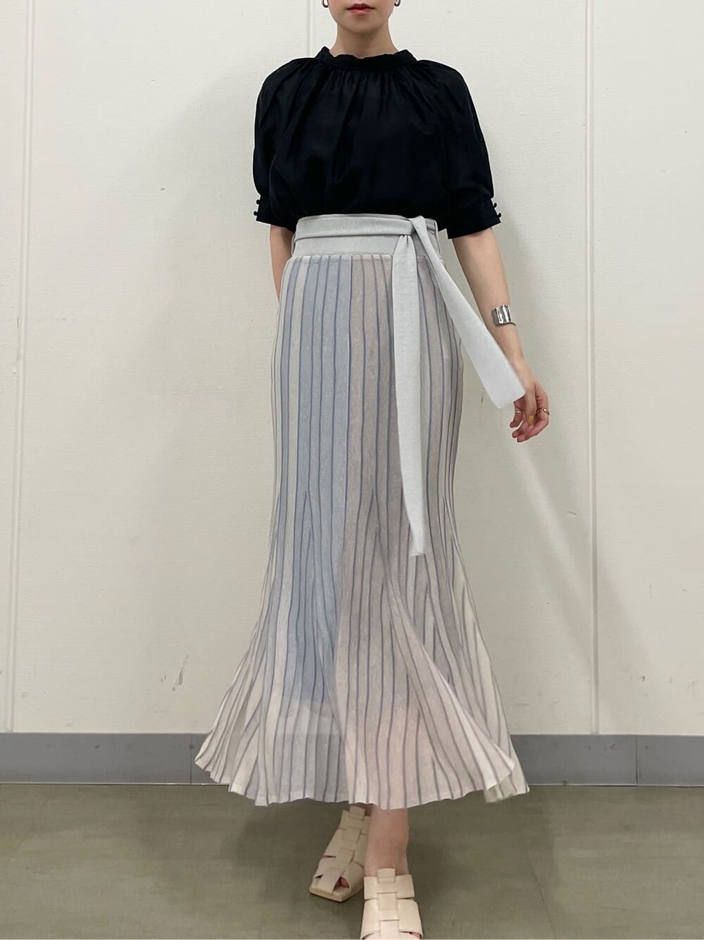 ブルー系のスカート、ホワイト系のサンダル、ブラック系のシャツ/ブラウスを着用したレディースの夏コーディネートの2枚目の写真