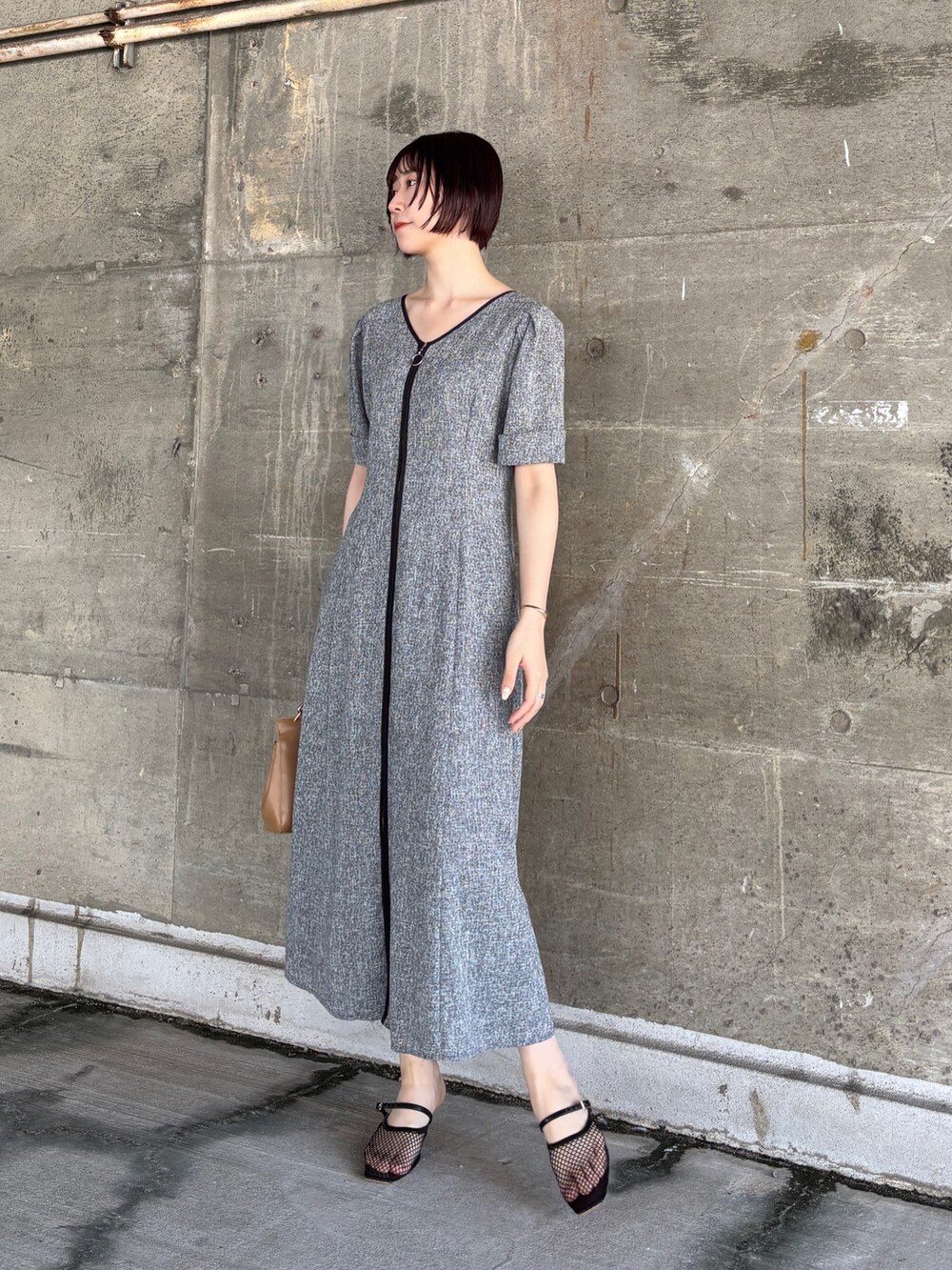 ブラック系のワンピース、イエロー系のハンドバッグ、ブラック系のサンダルを着用したレディースの夏コーディネートの2枚目の写真