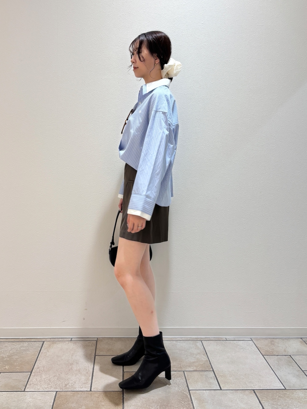 ブルー系のシャツ/ブラウス、ブラック系のハンドバッグ、ブラック系のブーツを着用したレディースの夏コーディネートの3枚目の写真