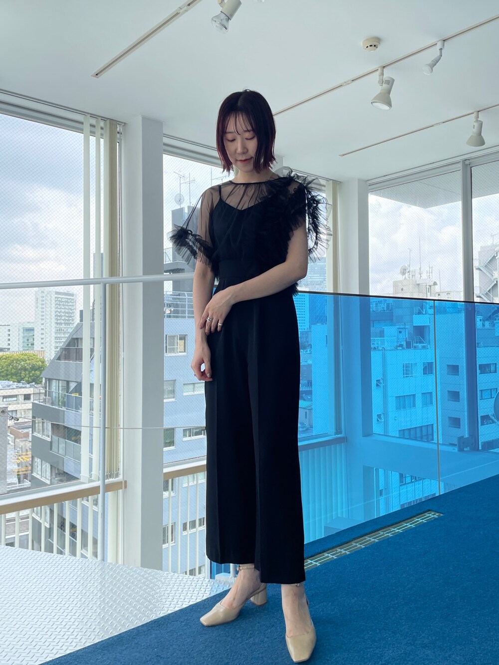 ブラック系のパンツドレス、ベージュ系のパンプスを着用したレディースの春コーディネートの2枚目の写真
