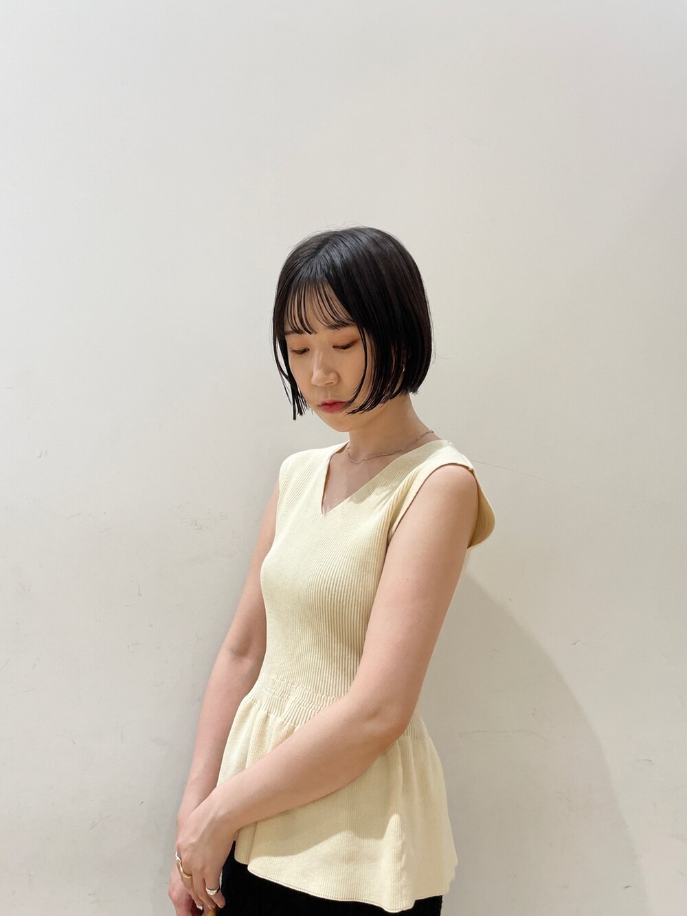 ベージュ系のハンドバッグ、ホワイト系のニット/セーター、ブラック系のスカートを着用したレディースの夏コーディネートの6枚目の写真