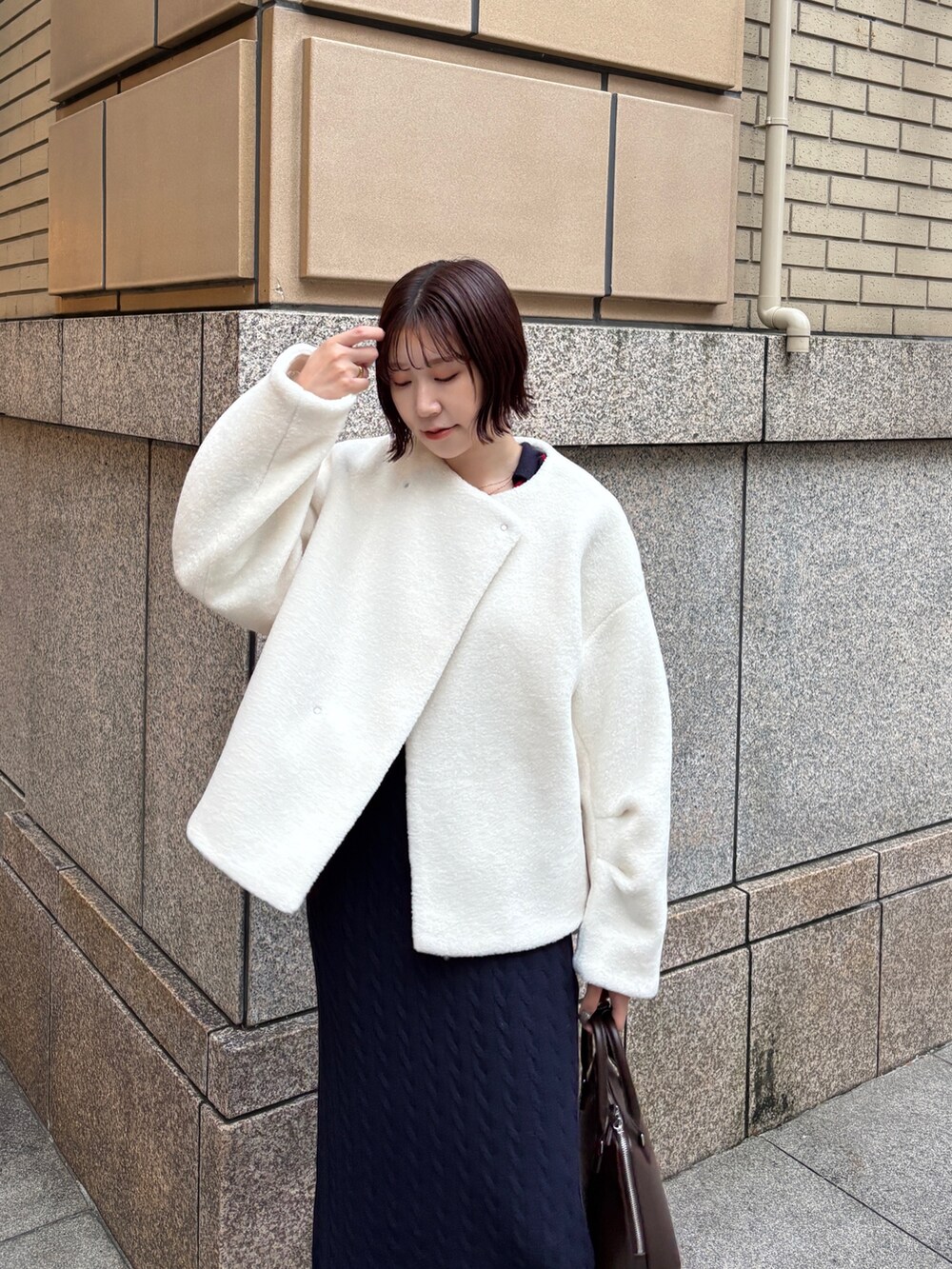 ホワイト系のブルゾン、ブルー系のワンピース、ブラウン系のボストンバッグを着用したレディースの秋コーディネートの6枚目の写真