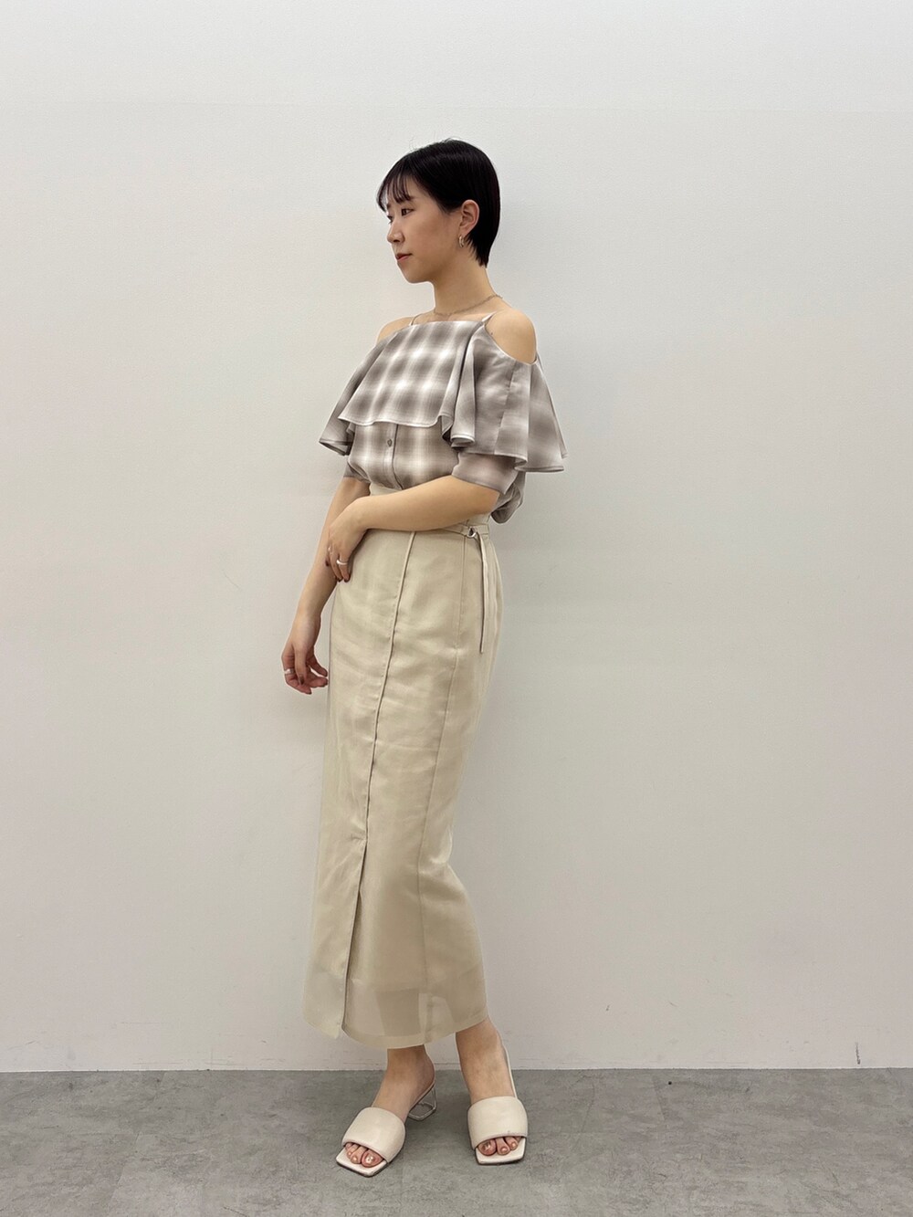 ベージュ系のシャツ/ブラウス、ホワイト系のスカート、ホワイト系のサンダルを着用したレディースの春コーディネートの3枚目の写真